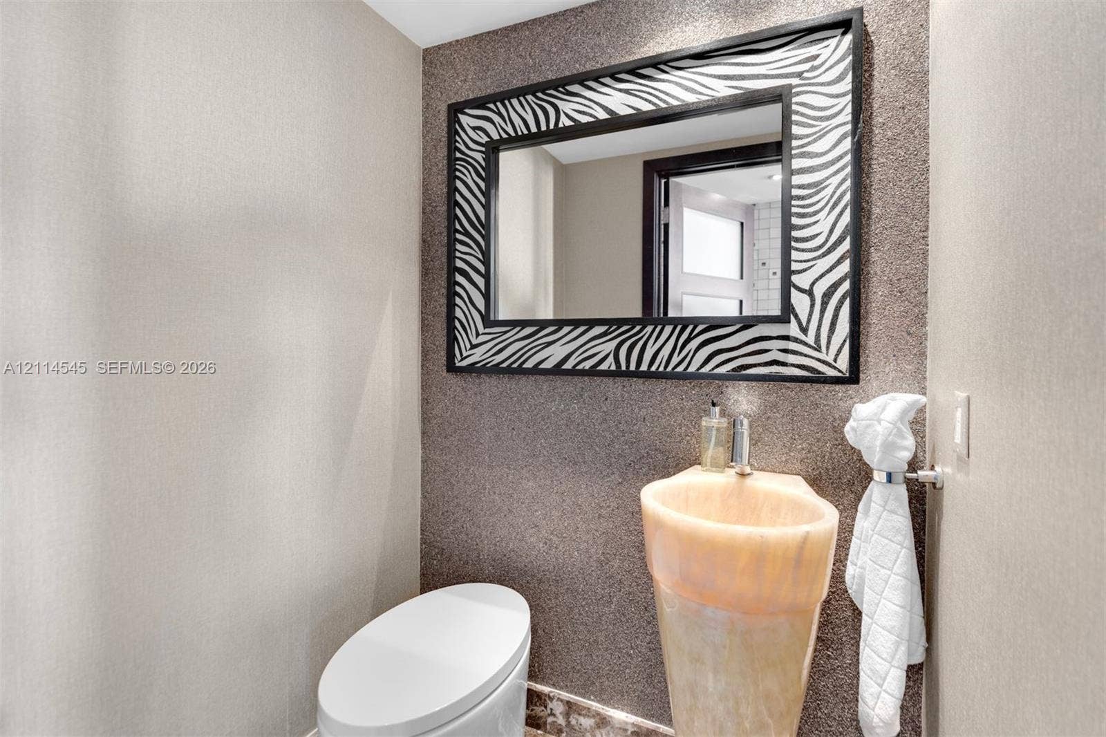 5875 Collins Avenue, #1503, Miami Beach, FL 33140 Textured wall finish, pedestal sink with integrated basin, and rectangular wall mirror