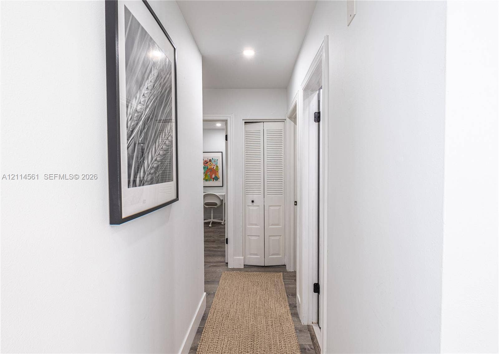 Hallway featuring recessed ceiling lighting, louvered bi-fold closet doors, and wood-finish flooring