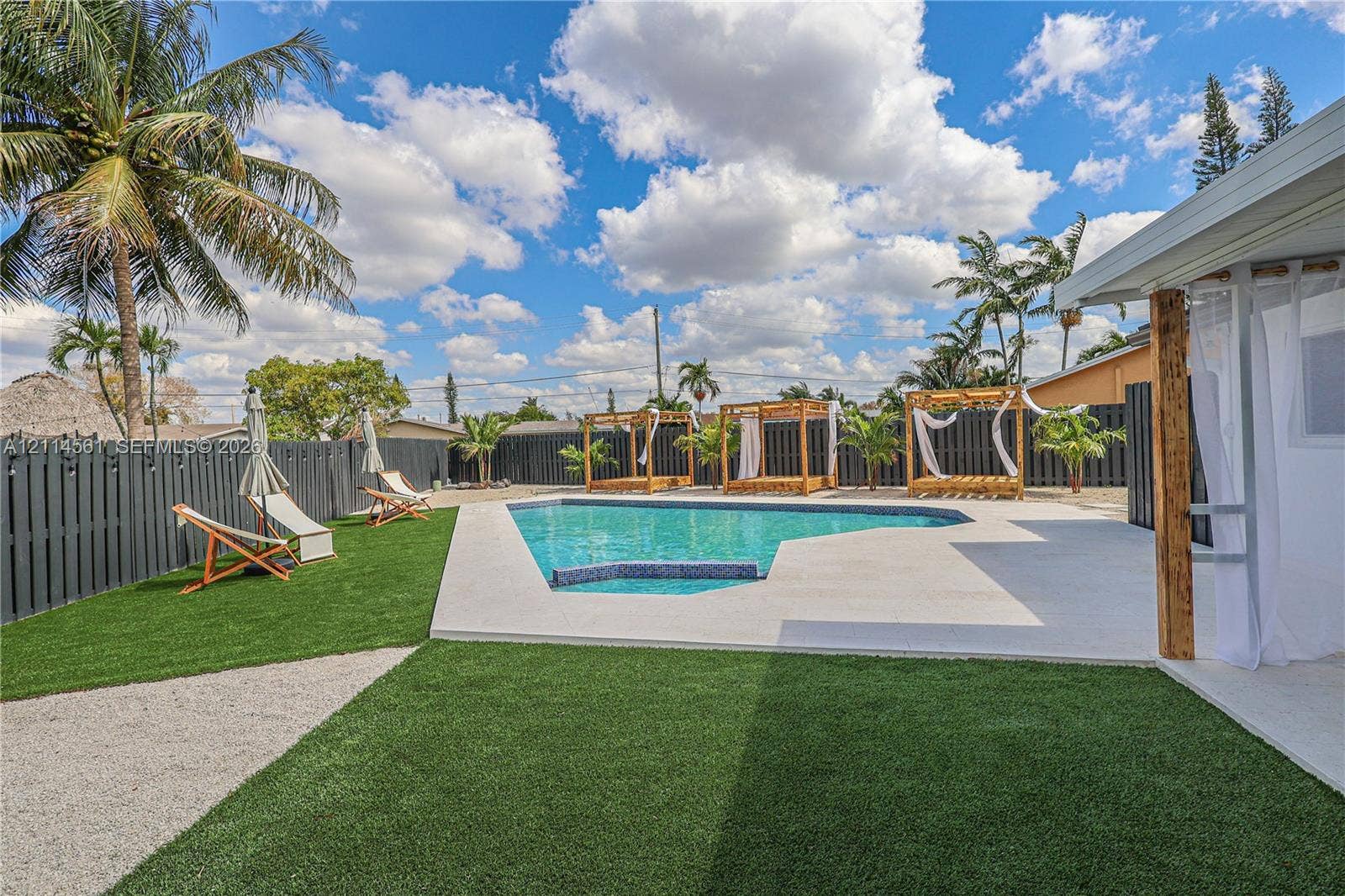 Outdoor space featuring an in-ground swimming pool, concrete pool deck, synthetic turf, and perimeter privacy fencing