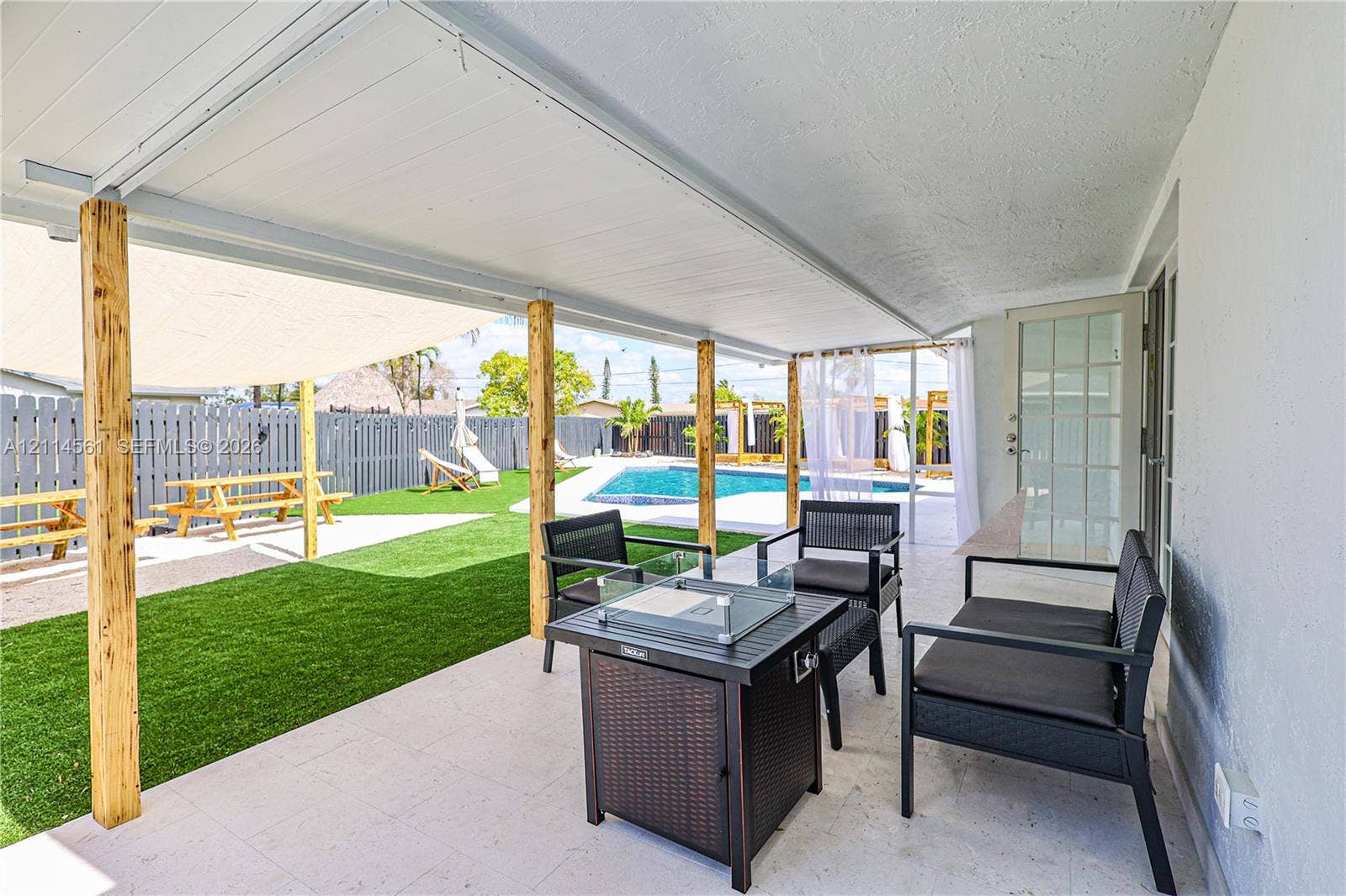 Covered patio featuring a solid-surface ceiling, natural wood support columns, tile flooring, and a swimming pool with a concrete pool deck