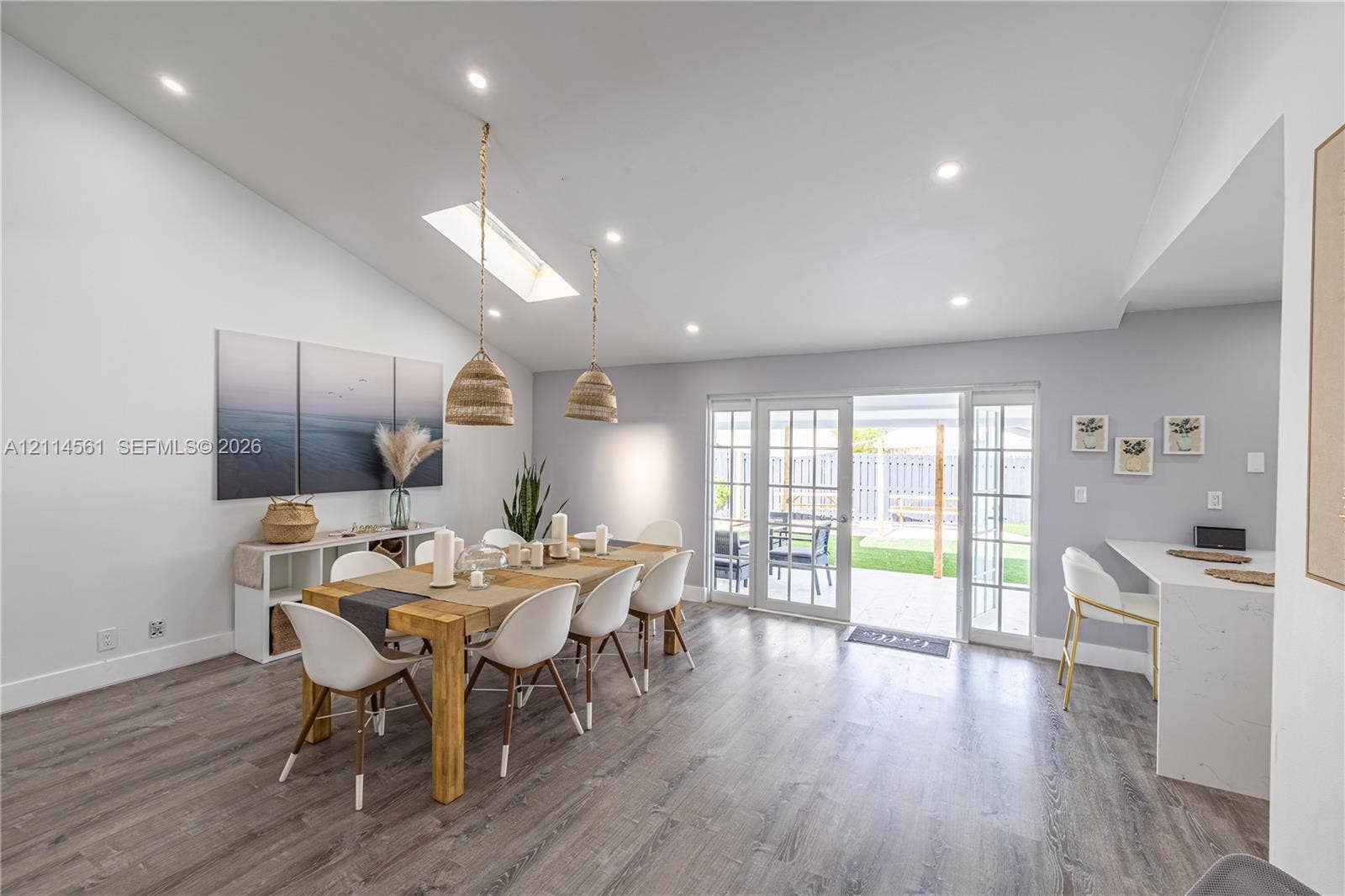 Vaulted ceiling with skylight, recessed lighting, wood-finish flooring, and white glass-pane French doors