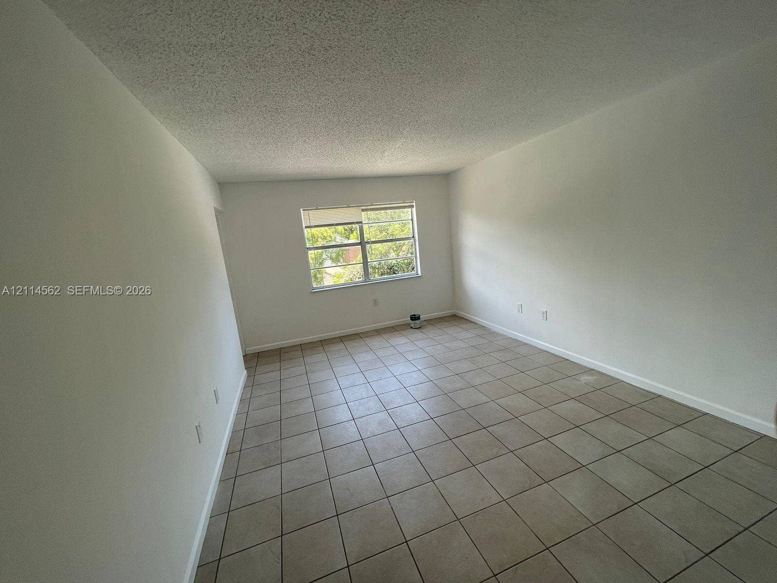 Interior room featuring neutral wall finishes, tile flooring, and a window with horizontal blinds