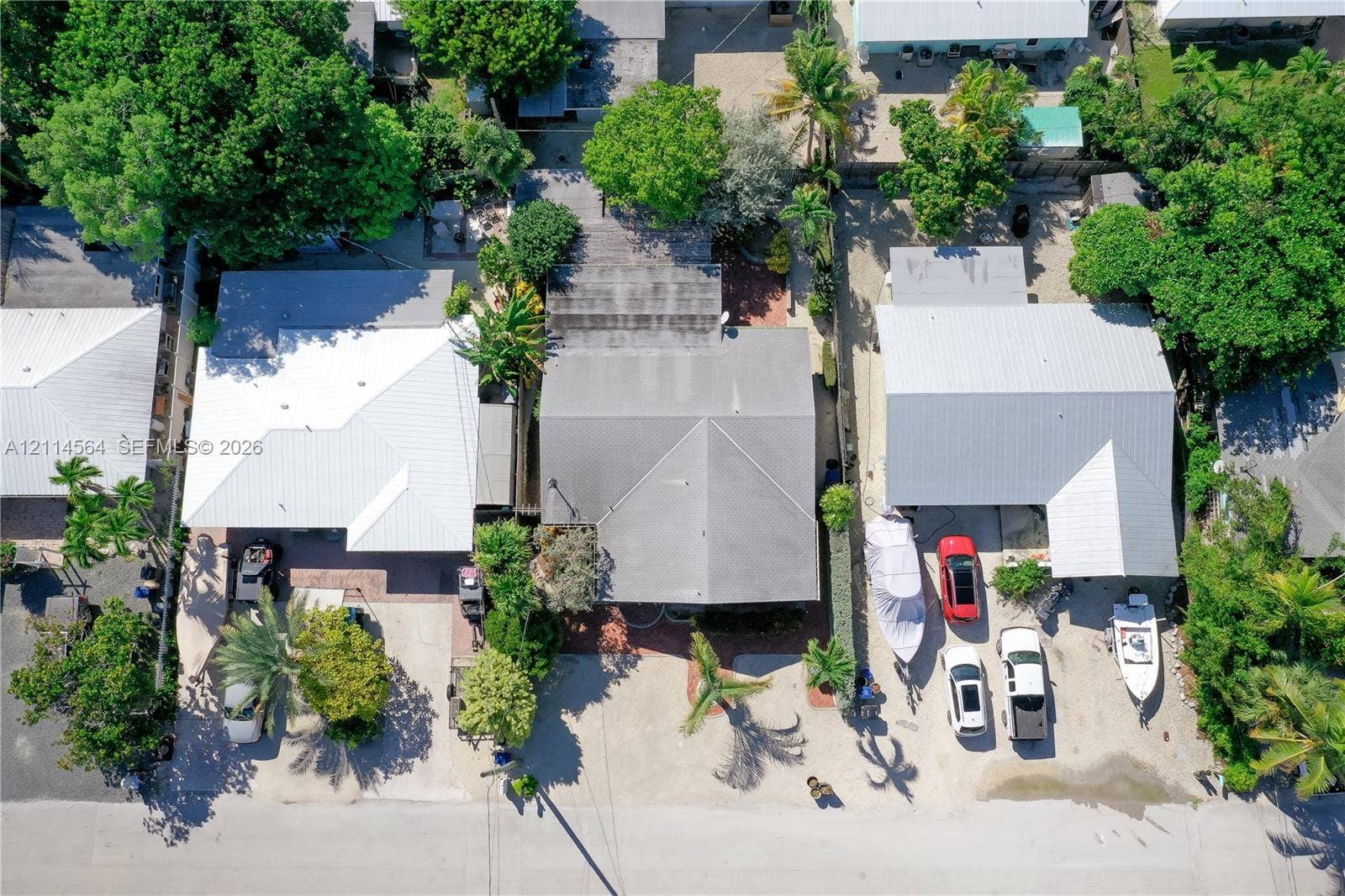 Aerial perspective featuring residential structures with metal roofing, paved driveways, and mature landscaping