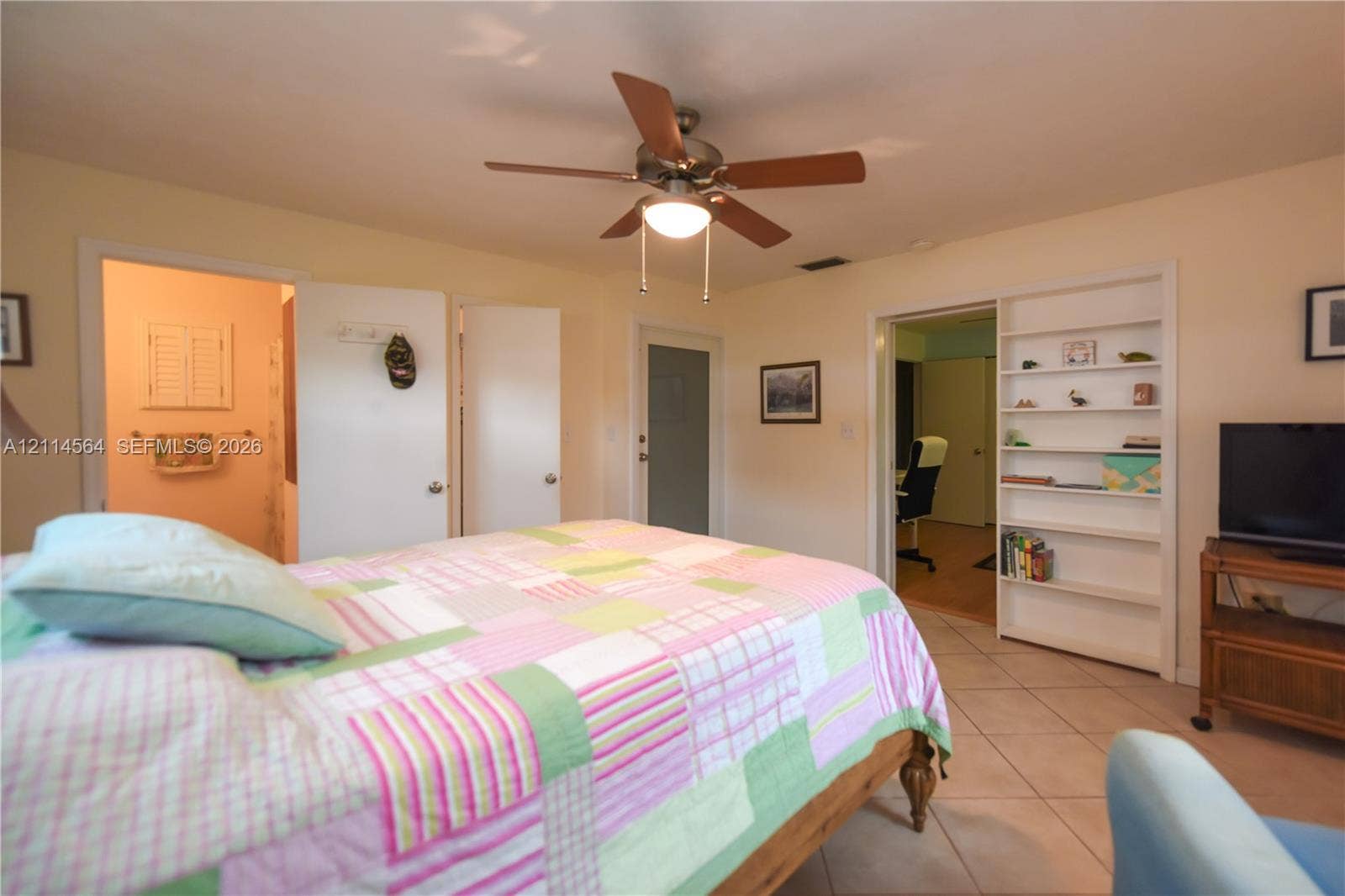 Room featuring tile flooring, a central ceiling fan with integrated lighting, and built-in wall shelving