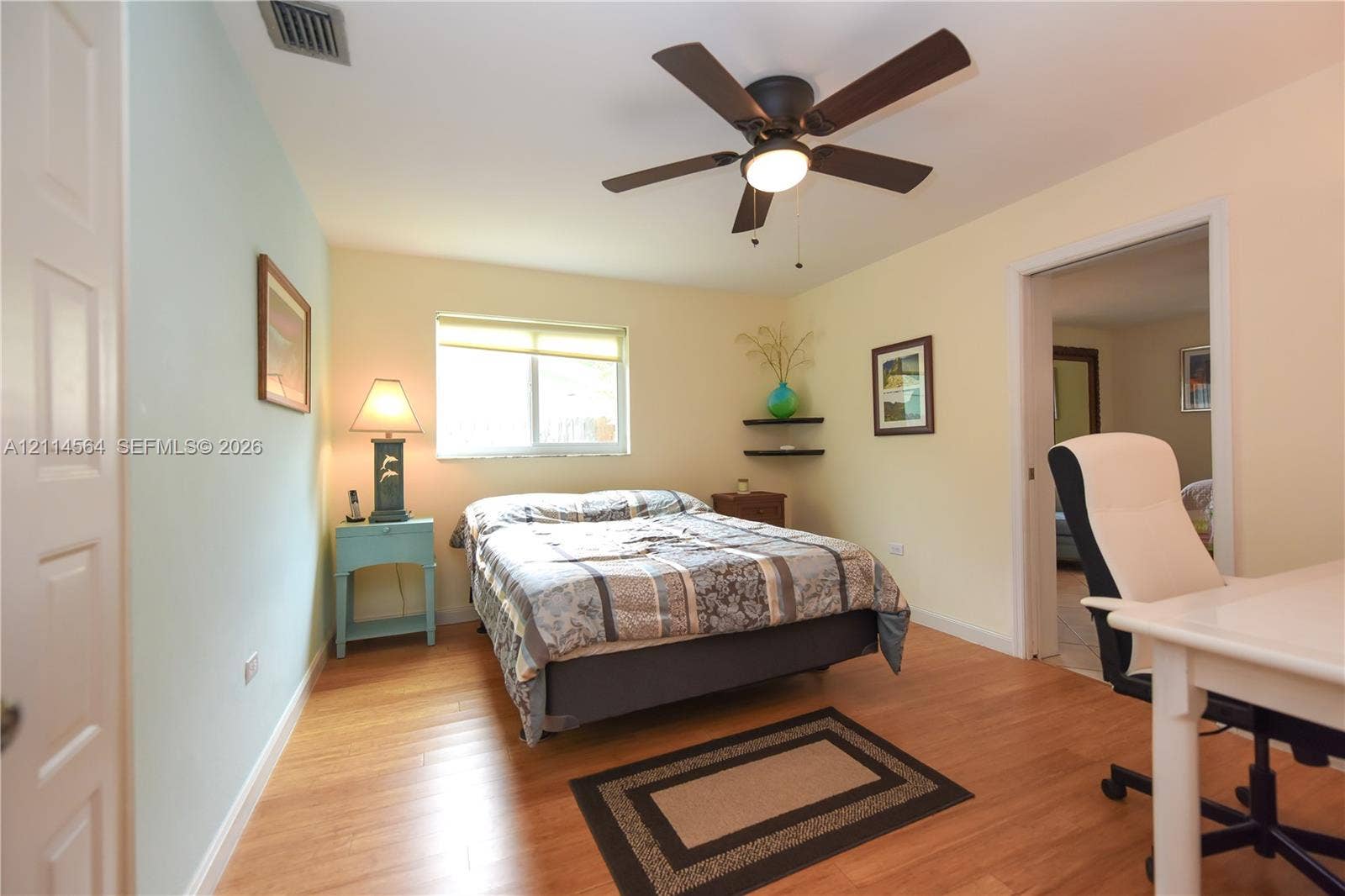 Room featuring wood-finish flooring, a ceiling fan with integrated lighting, and built-in corner shelving