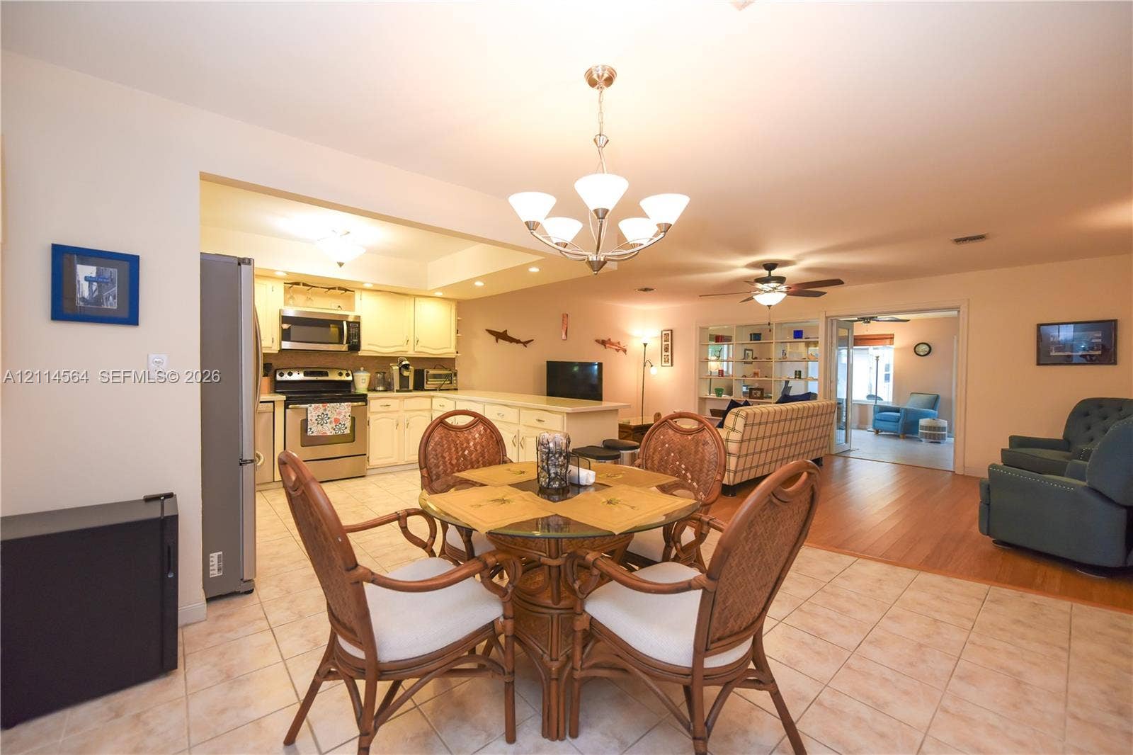 Kitchen area featuring light-toned cabinetry, stainless steel appliances, a multi-arm chandelier, wood-finish flooring, and ceramic tile flooring
