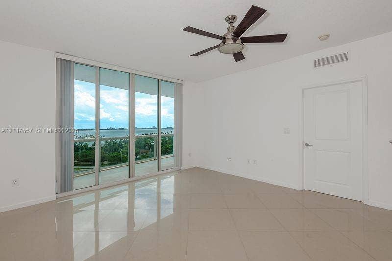 Floor-to-ceiling glass sliders, tile flooring, and a five-blade ceiling fan featuring a brushed nickel finish