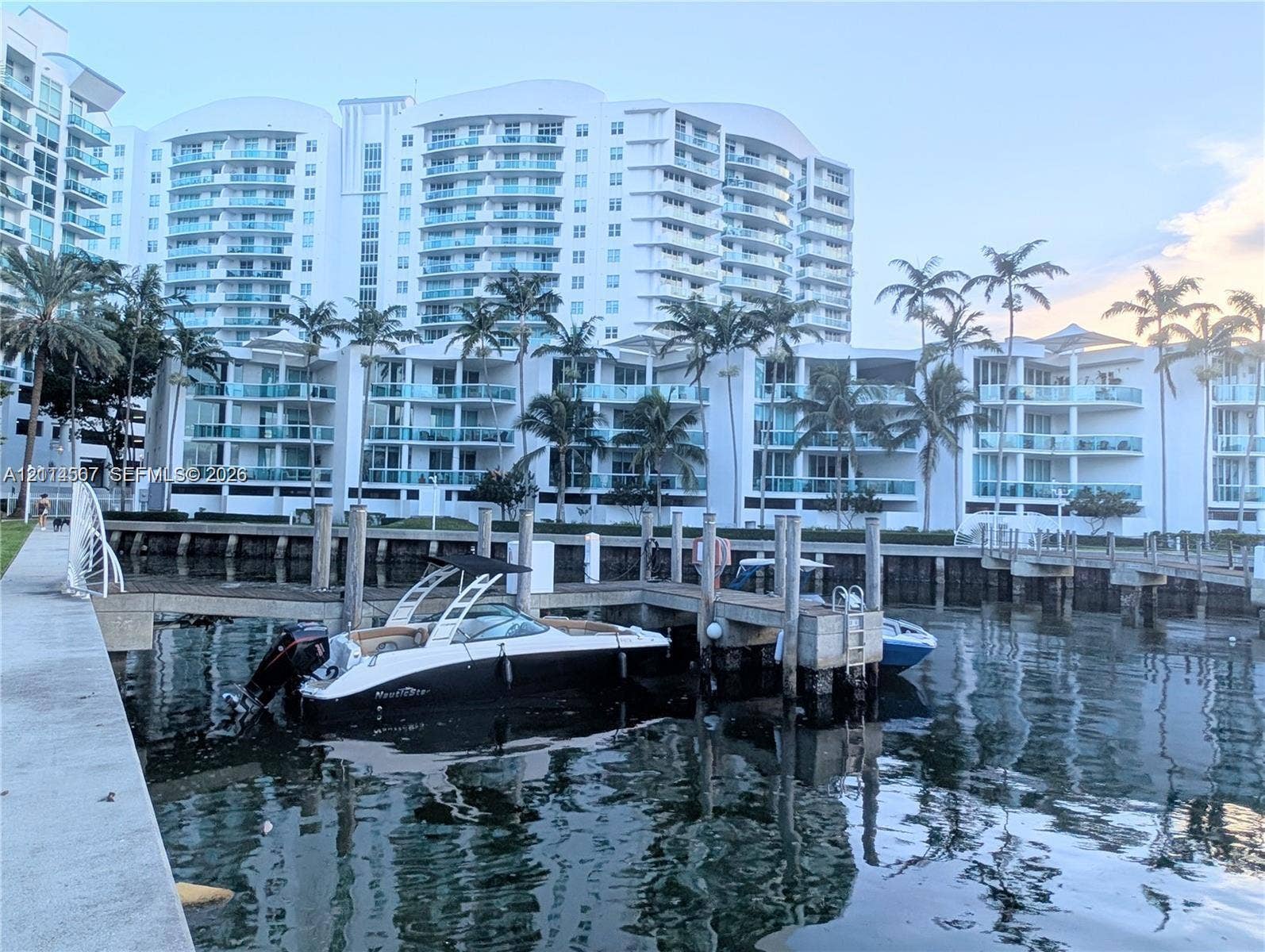 Waterfront high-rise building featuring private deep-water dockage, tiered balconies with glass railings, and mature palm landscaping