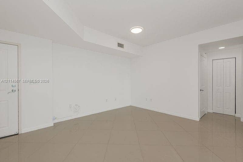 Interior space featuring large-format tile flooring, crisp white walls, recessed lighting, and a bi-fold closet