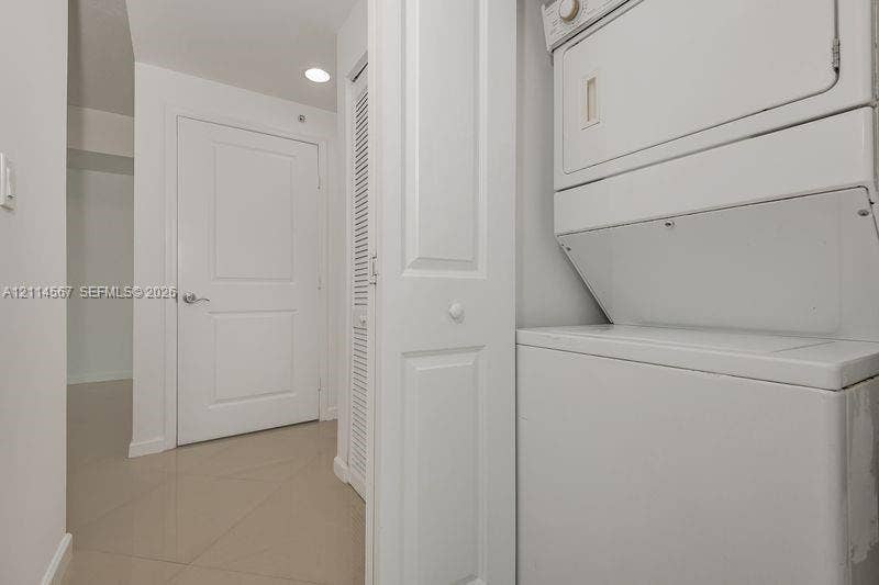 Stacked laundry unit, louvered bi-fold closet door, recessed lighting, and panel-style interior door