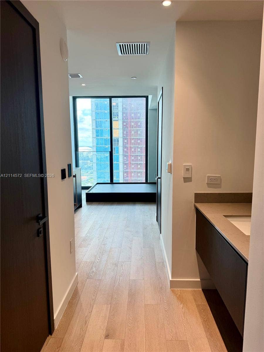 20 NE 11, #3312B, Miami, FL 33132 Floor-to-ceiling windows, wood-finish flooring, floating vanity with a neutral-toned countertop, and dark-toned interior doors