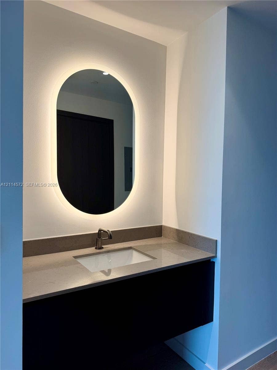 20 NE 11, #3312B, Miami, FL 33132 Floating vanity with stone countertop, undermount sink, metallic faucet, and oval back-lit mirror