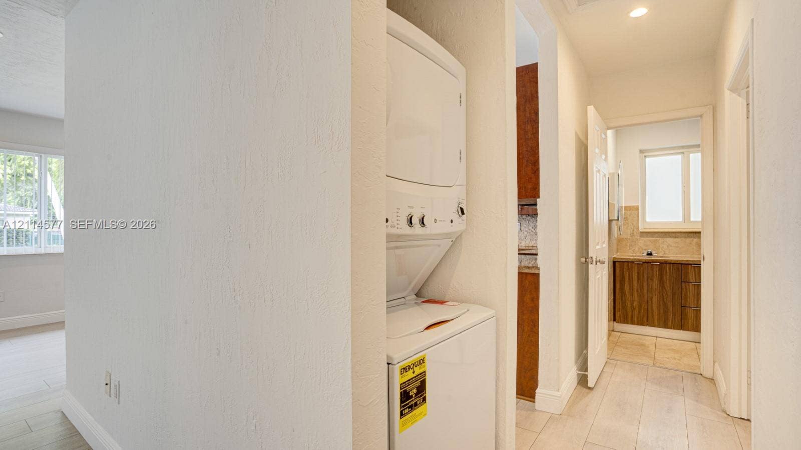 311 SW 38th Court, #0, Miami, Miami, FL 33134 Laundry alcove featuring a stacked appliance unit, tiled flooring, and neutral wall finishes