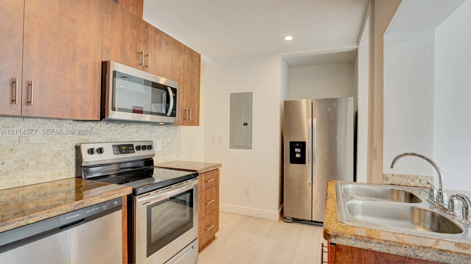 311 SW 38th Court, #0, Miami, Miami, FL 33134 Kitchen featuring wood-finish cabinetry, stone-texture backsplash, stainless steel appliances, and solid-surface countertops with a dual-basin undermount sink