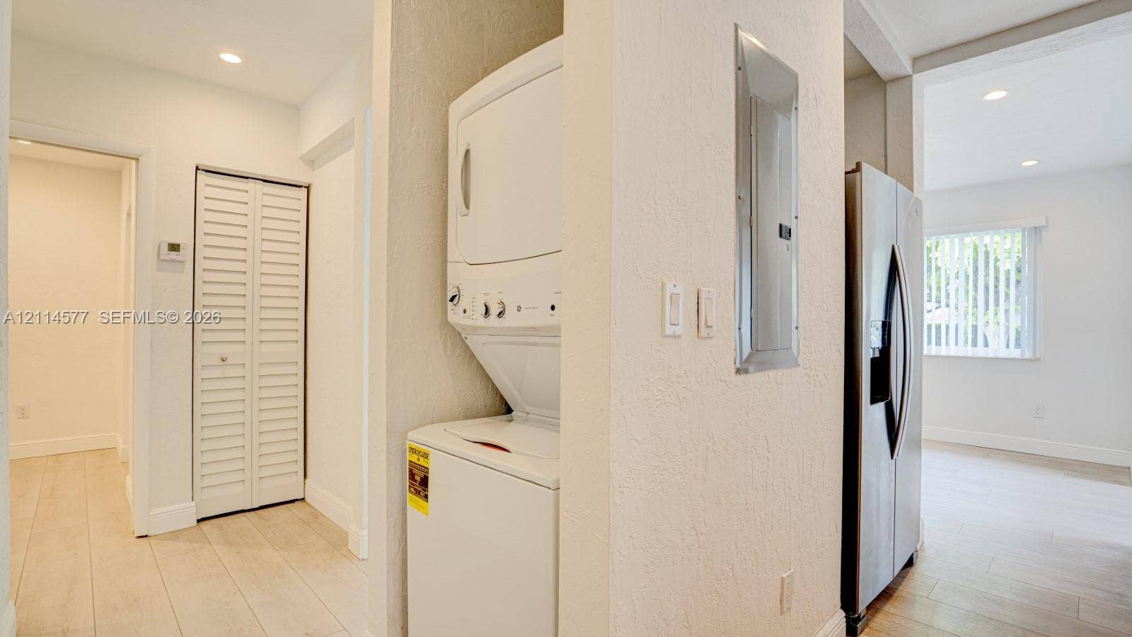 311 SW 38th Court, #0, Miami, Miami, FL 33134 Laundry closet featuring a stackable washer and dryer, wood-finish flooring, recessed lighting, and a louvered bifold door