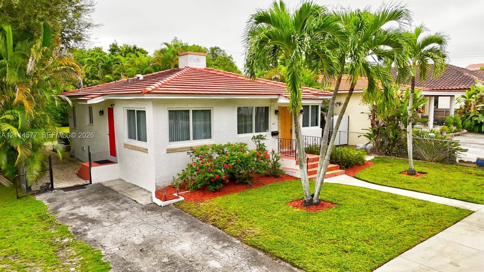 311 SW 38th Court, #0, Miami, Miami, FL 33134 Single-story exterior featuring white stucco siding, a tiled hip roof, a concrete driveway, and mature palm landscaping