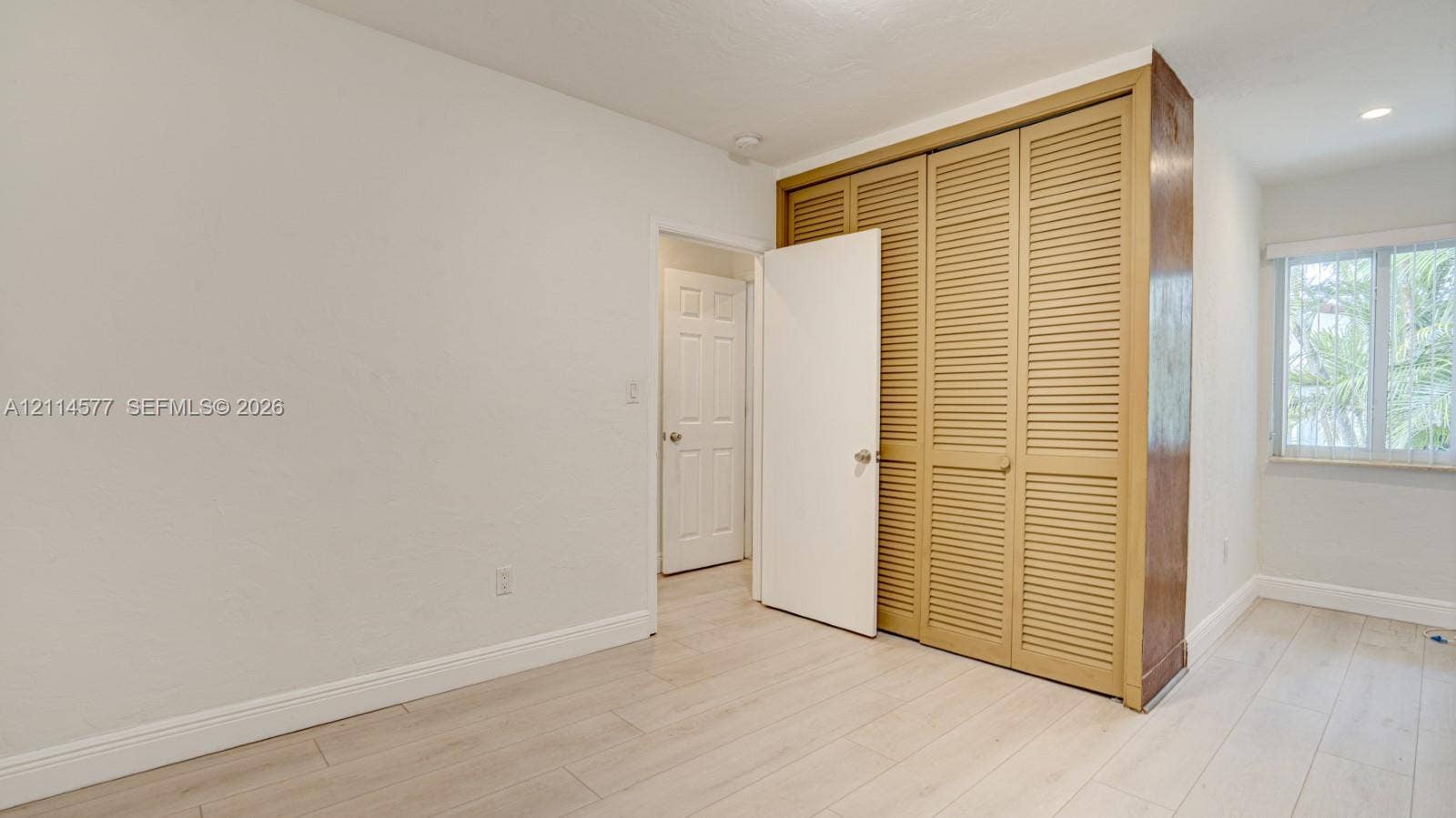 311 SW 38th Court, #0, Miami, Miami, FL 33134 Neutral interior space featuring wood-finish flooring, louvered closet doors, and a window with white casing