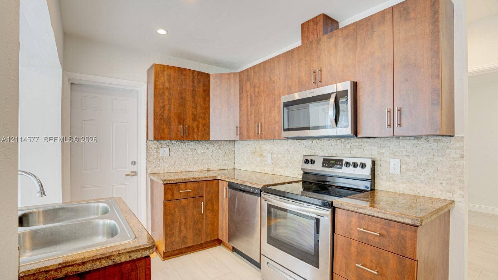 311 SW 38th Court, #0, Miami, Miami, FL 33134 Kitchen featuring flat-panel wood-finish cabinetry, stone-surface countertops, textured stone backsplash, stainless steel appliances, and a double-basin sink
