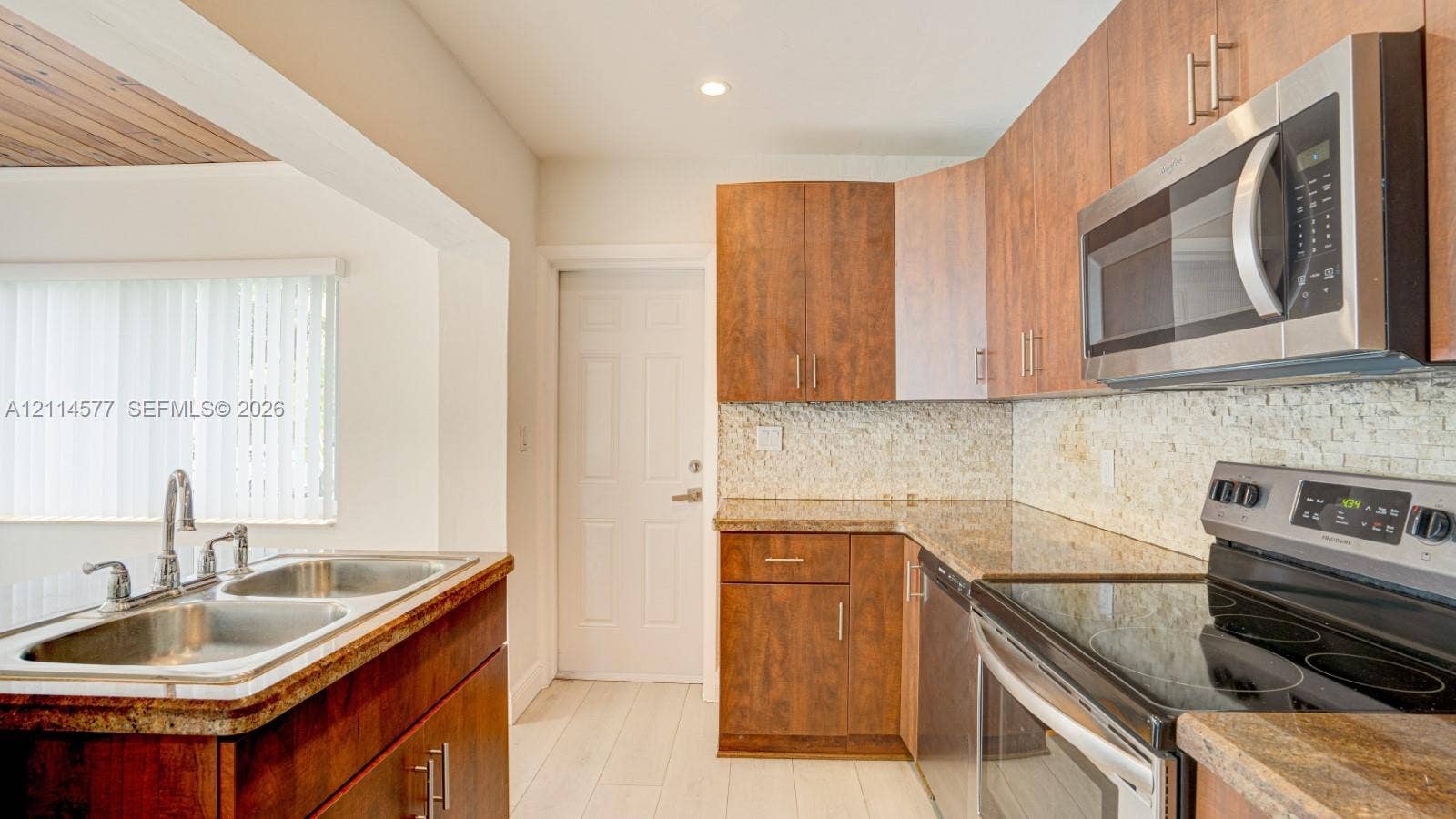 311 SW 38th Court, #0, Miami, Miami, FL 33134 Kitchen featuring wood-finish cabinetry, stone-texture countertops, a mosaic tile backsplash, and stainless steel appliances