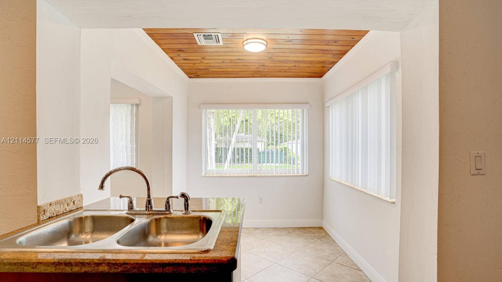 311 SW 38th Court, #0, Miami, Miami, FL 33134 Double-basin stainless steel sink with high-arc faucet, stone-surfaced countertop, natural wood-paneled ceiling, and ceramic tile flooring