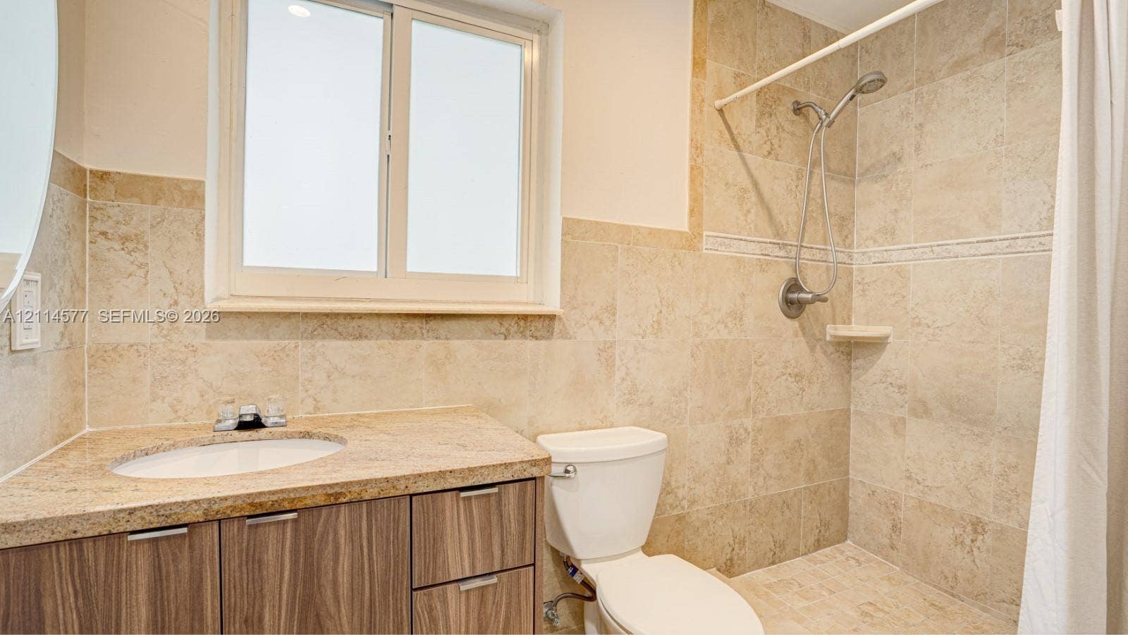 311 SW 38th Court, #0, Miami, Miami, FL 33134 Bathroom featuring stone-tile wall surround, wood-finish vanity cabinetry, stone-slab countertop with integrated oval sink, and a handheld shower fixture