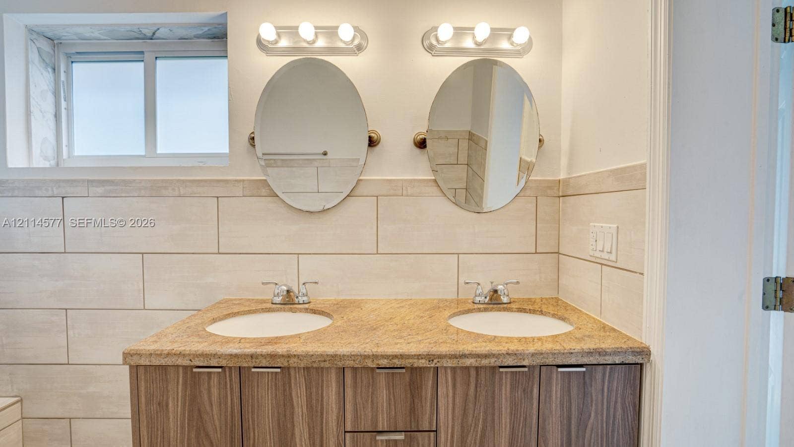 311 SW 38th Court, #0, Miami, Miami, FL 33134 Double vanity featuring a stone countertop, dual undermount sinks, wood-finish cabinetry, two oval mirrors, and horizontal tile wall surrounds
