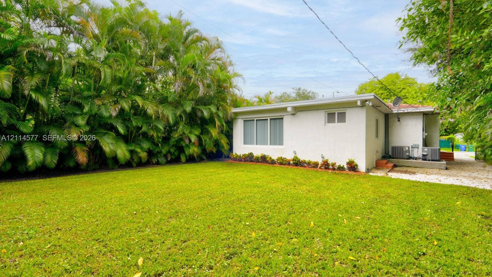 311 SW 38th Court, #0, Miami, Miami, FL 33134 Expansive lawn area featuring mature perimeter palm trees, painted brick exterior, and multi-pane window configuration