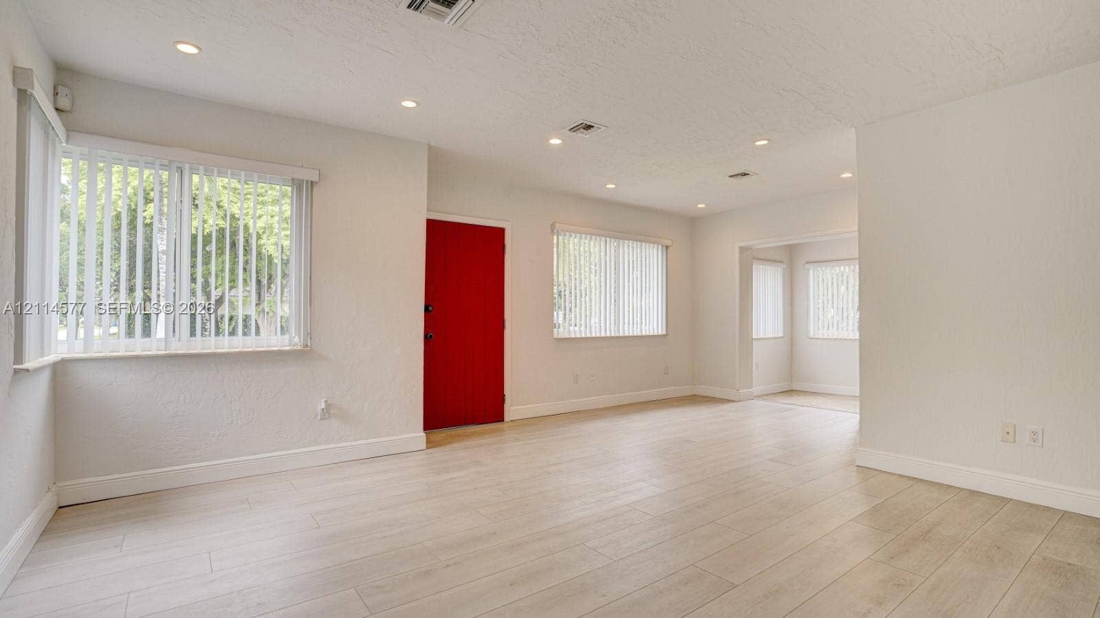 311 SW 38th Court, #0, Miami, Miami, FL 33134 Neutral interior featuring wood-finish flooring, recessed lighting, multiple windows with vertical blinds, and a solid red-finish front door