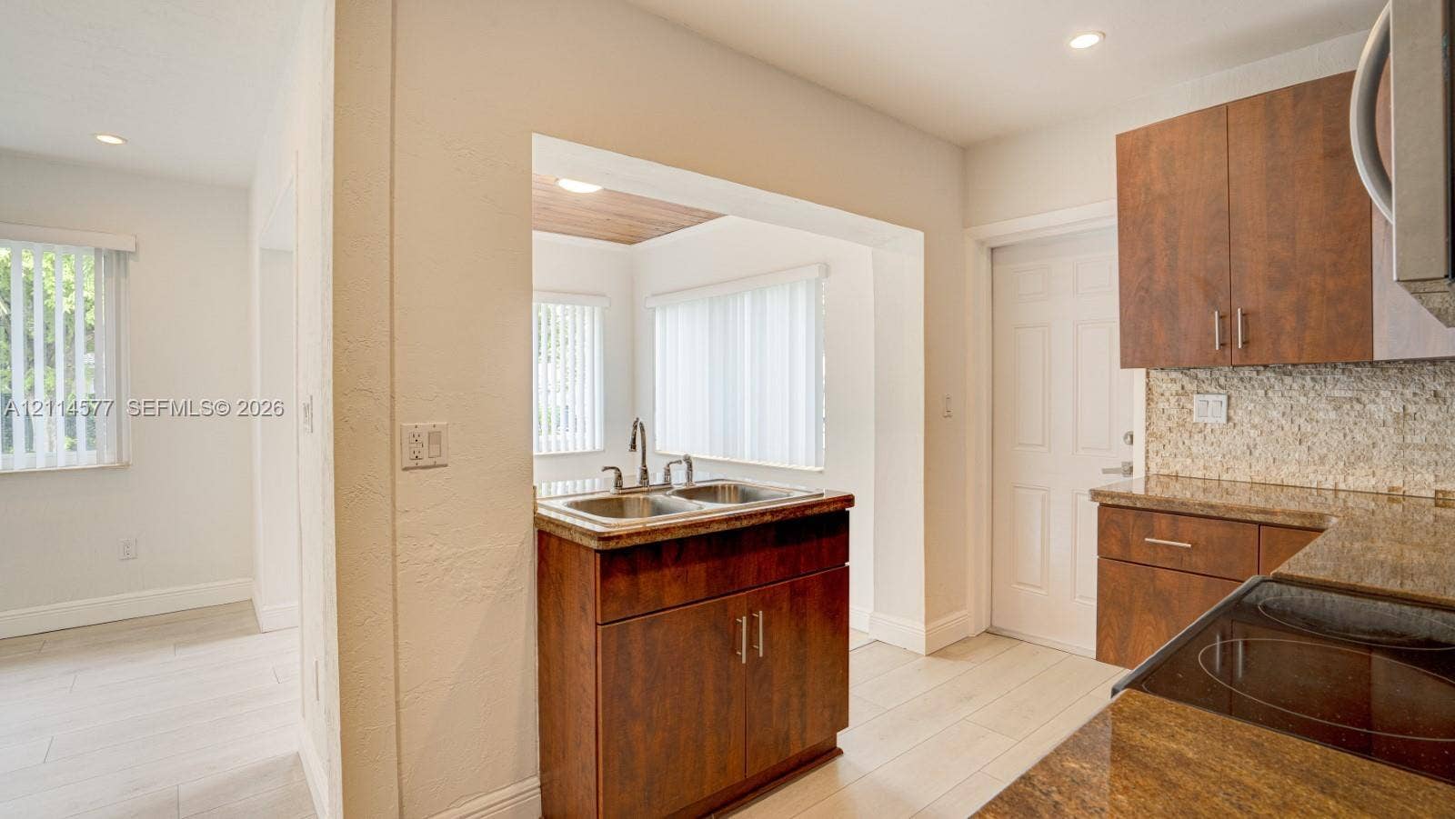 311 SW 38th Court, #0, Miami, Miami, FL 33134 Kitchen featuring wood-finish cabinetry, stone-texture countertops, a dual-basin stainless steel sink, tiled backsplash, and light-toned wood-finish flooring