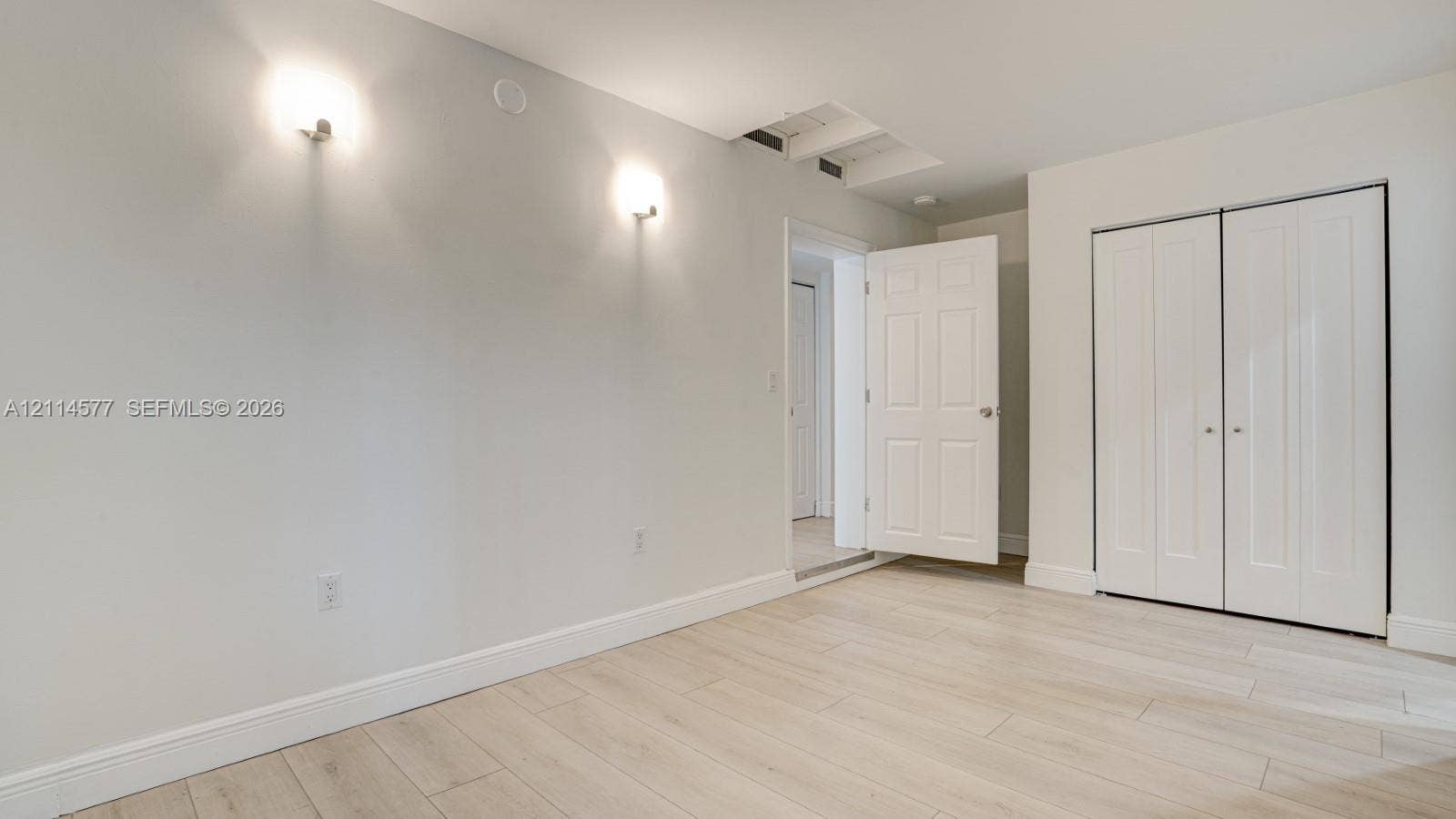 311 SW 38th Court, #0, Miami, Miami, FL 33134 Interior space featuring light-toned wood-finish flooring, neutral walls, two wall-mounted light fixtures, and a white six-panel closet door