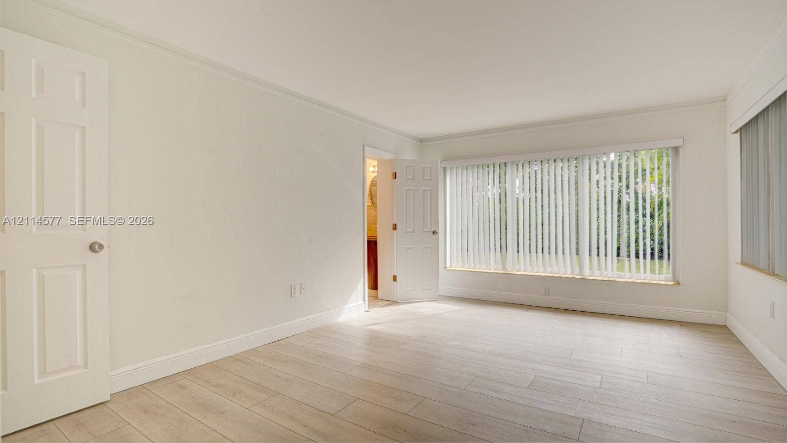 311 SW 38th Court, #0, Miami, Miami, FL 33134 Neutral-toned interior featuring wood-finish flooring, six-panel doors, and large windows with vertical blinds