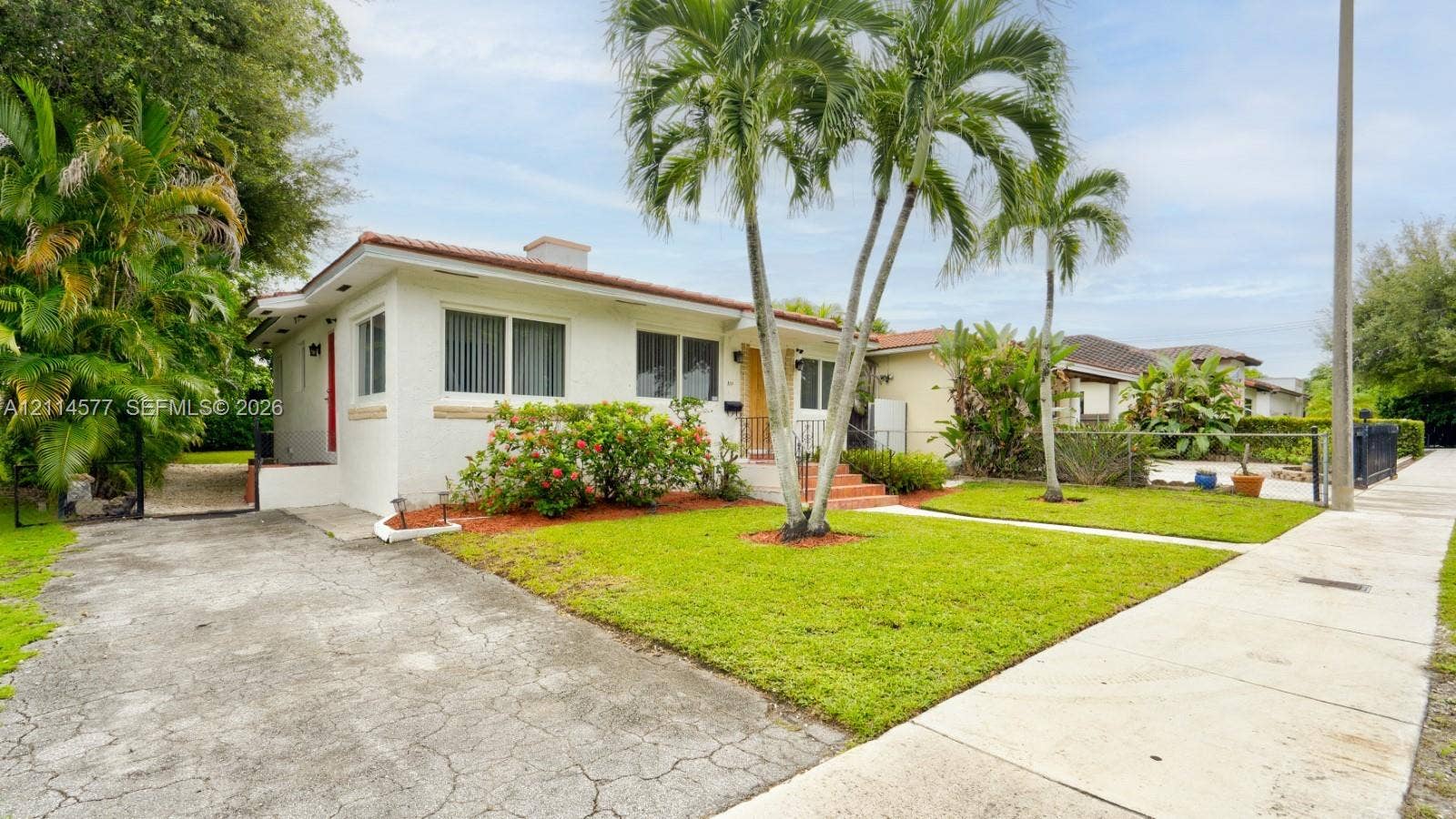 311 SW 38th Court, #0, Miami, Miami, FL 33134 Stucco exterior residence featuring a tiled roof, concrete driveway, mature palm trees, and manicured landscaping