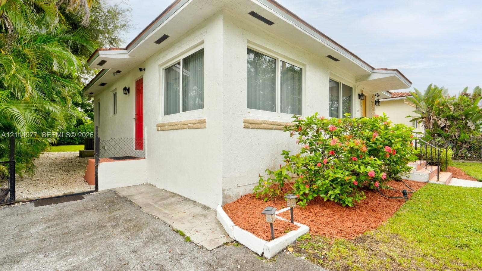 311 SW 38th Court, #0, Miami, Miami, FL 33134 Exterior featuring stucco siding, stone sill accents, sliding windows, and a paved side driveway with gravel path