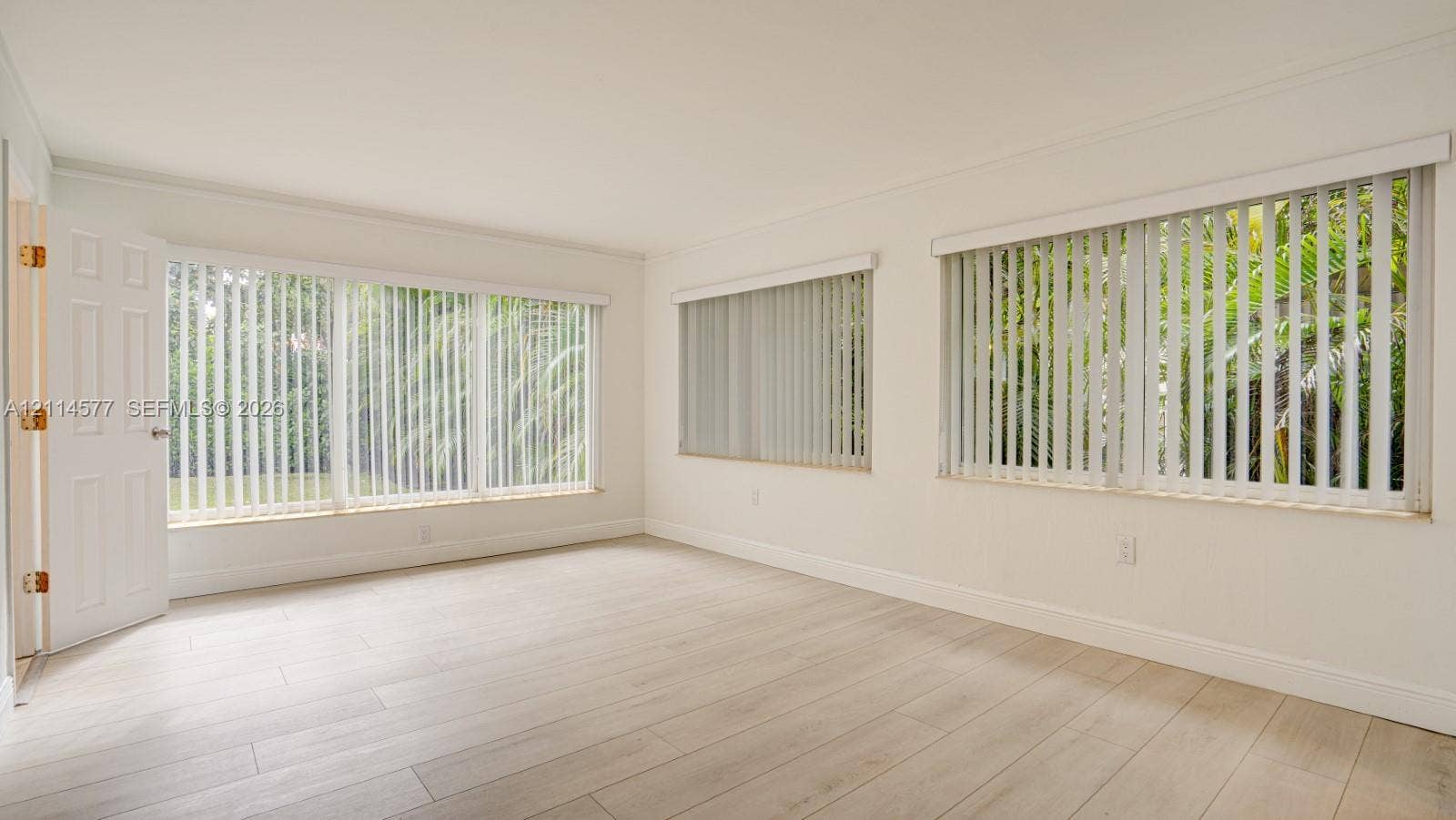 311 SW 38th Court, #0, Miami, Miami, FL 33134 Interior space featuring wood-finish flooring, multi-pane windows with vertical blinds, and a paneled entry door