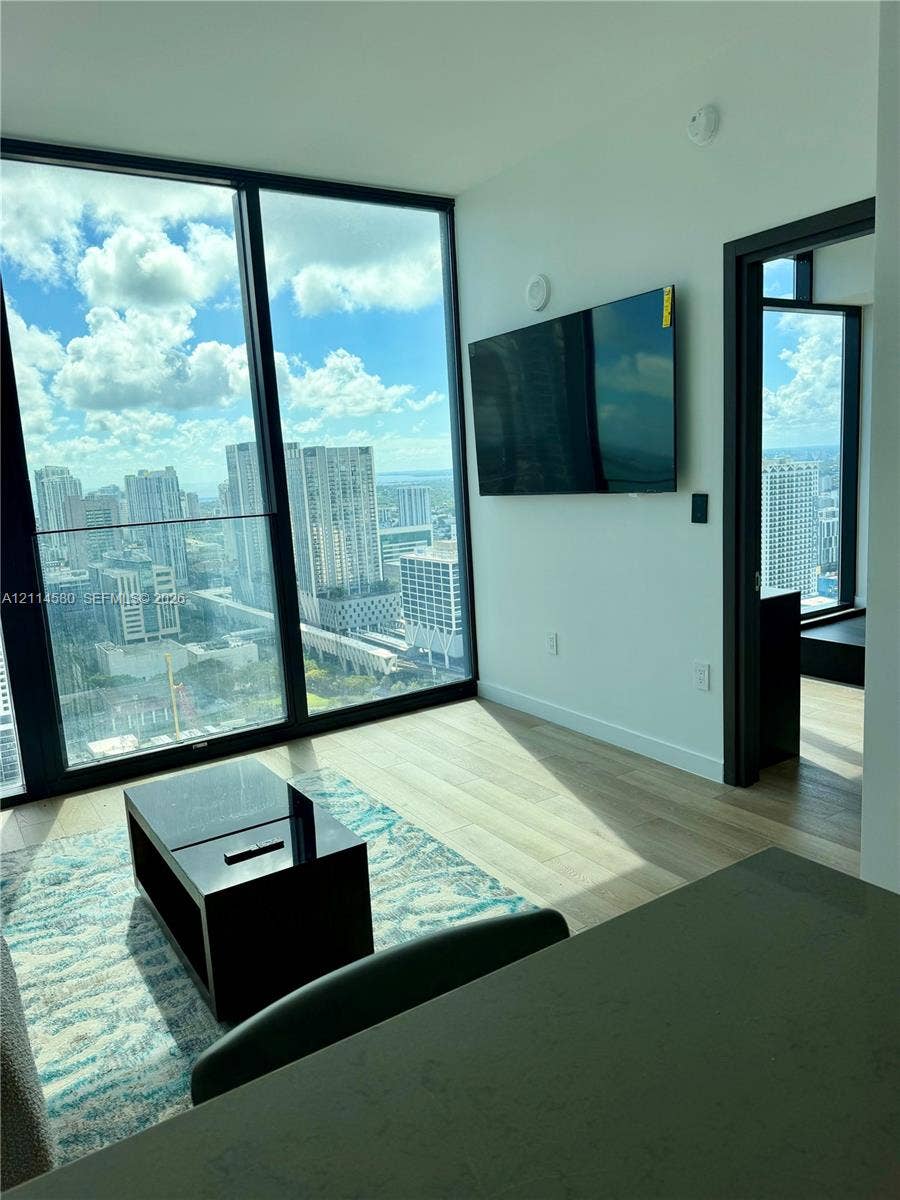 20 NE 11, #4109, Miami, FL 33132 Floor-to-ceiling windows with urban skyline scenery, wood-finish flooring, and black door frames