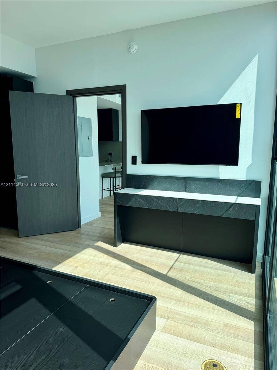 20 NE 11, #4109, Miami, FL 33132 Custom built-in console featuring stone-finish surfacing, light wood-finish flooring, and dark-toned interior doors