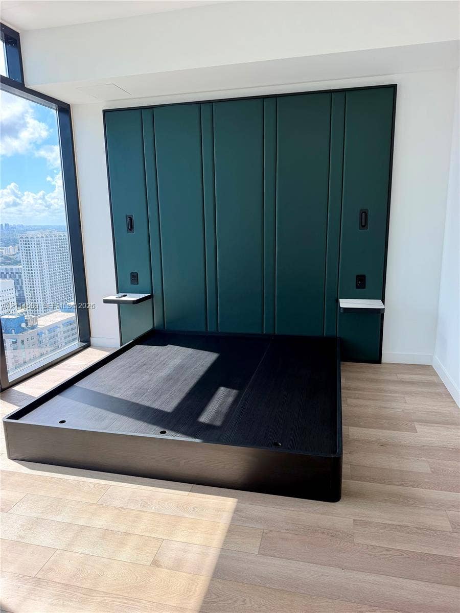 20 NE 11, #4109, Miami, FL 33132 Floor-to-ceiling windows, custom emerald green paneled accent wall, wood-finish flooring, and built-in floating side shelves