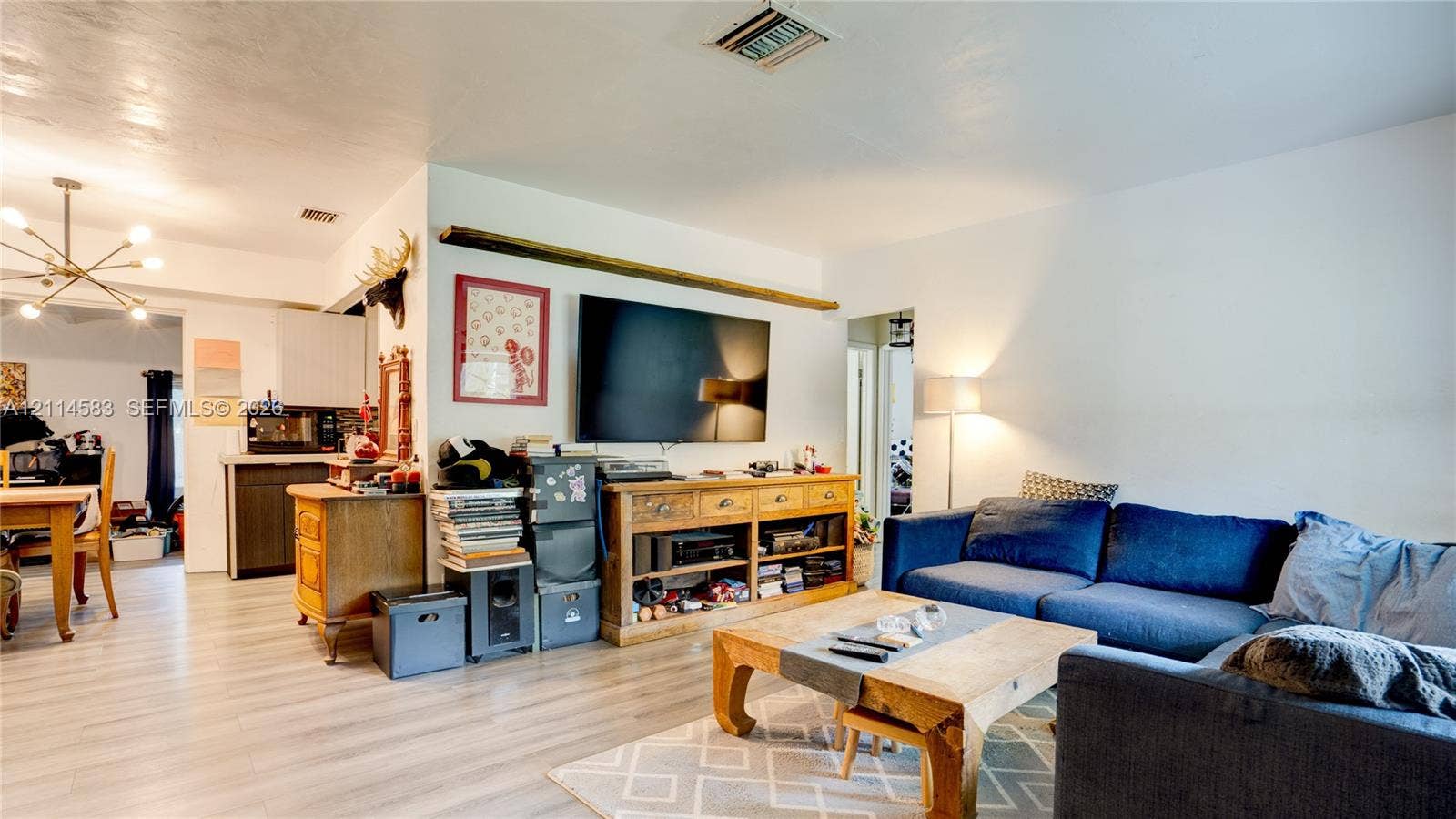 13301 NW Miami Court, Miami, FL 33168 Open-concept area featuring light-tone wood-finish flooring and a multi-arm modern light fixture