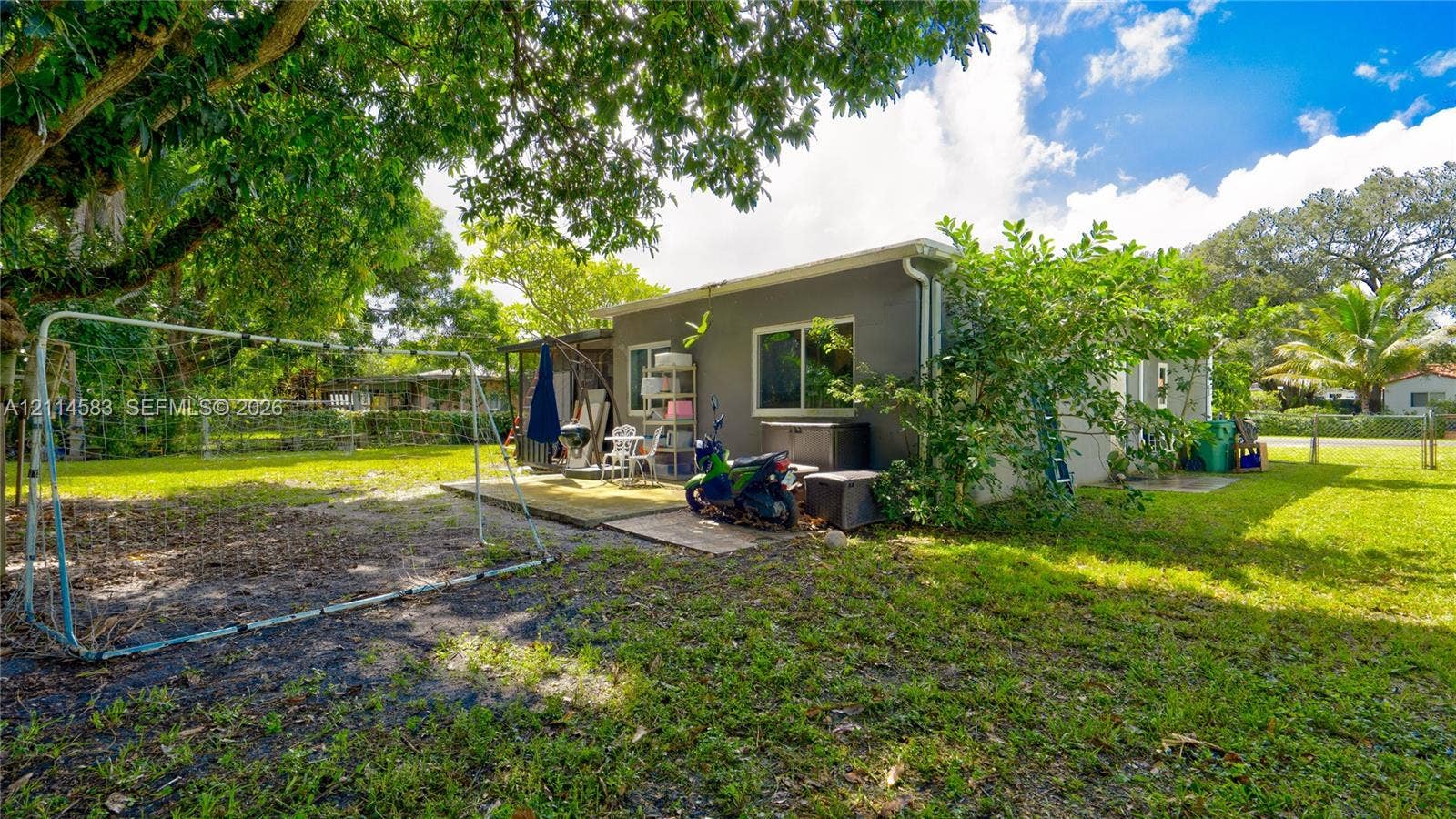 13301 NW Miami Court, Miami, FL 33168 Expansive backyard featuring mature shade trees, a concrete patio, and perimeter fencing