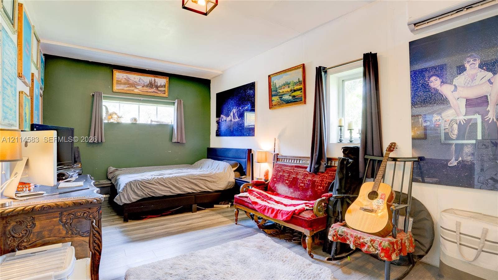 13301 NW Miami Court, Miami, FL 33168 Room featuring wood-finish flooring, two windows with horizontal panes, an olive green accent wall, and an overhead lighting fixture
