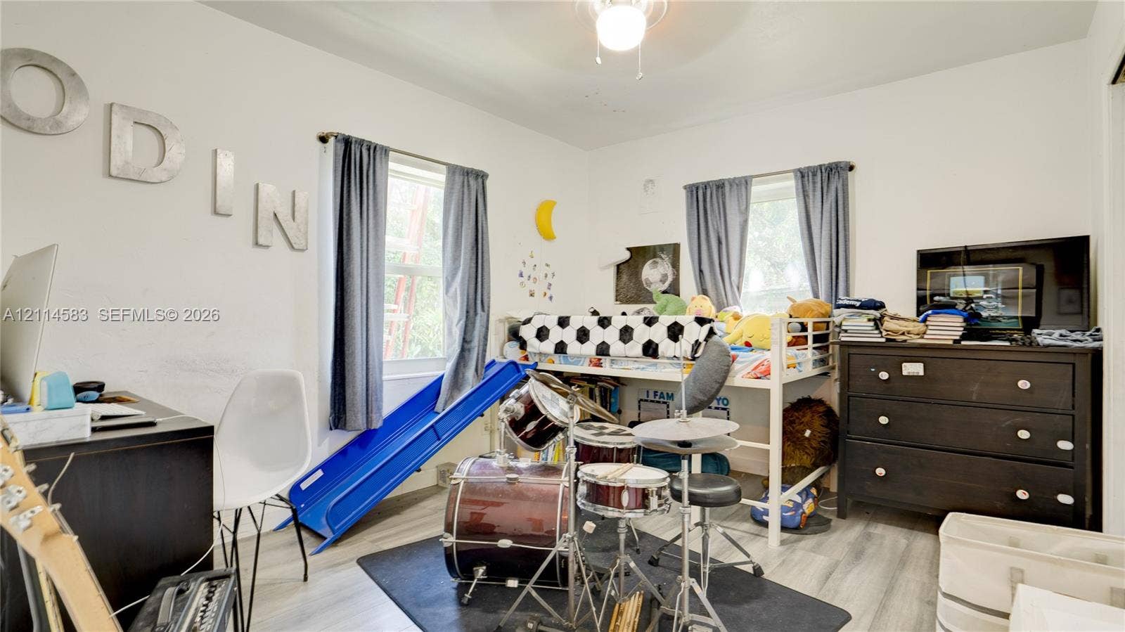 13301 NW Miami Court, Miami, FL 33168 Bedroom featuring light-toned wood-finish flooring, dual windows with integrated curtain rods, and a ceiling-mounted light fixture