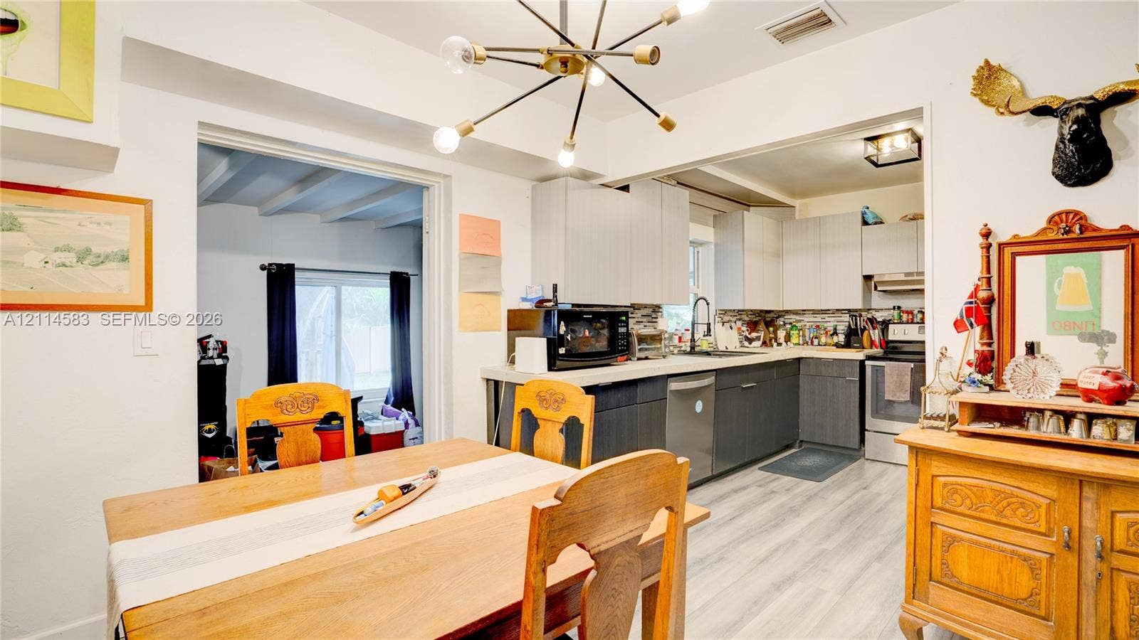 13301 NW Miami Court, Miami, FL 33168 Kitchen featuring two-toned cabinetry, light-toned countertop, wood-finish flooring, and a multi-arm sputnik-style light fixture