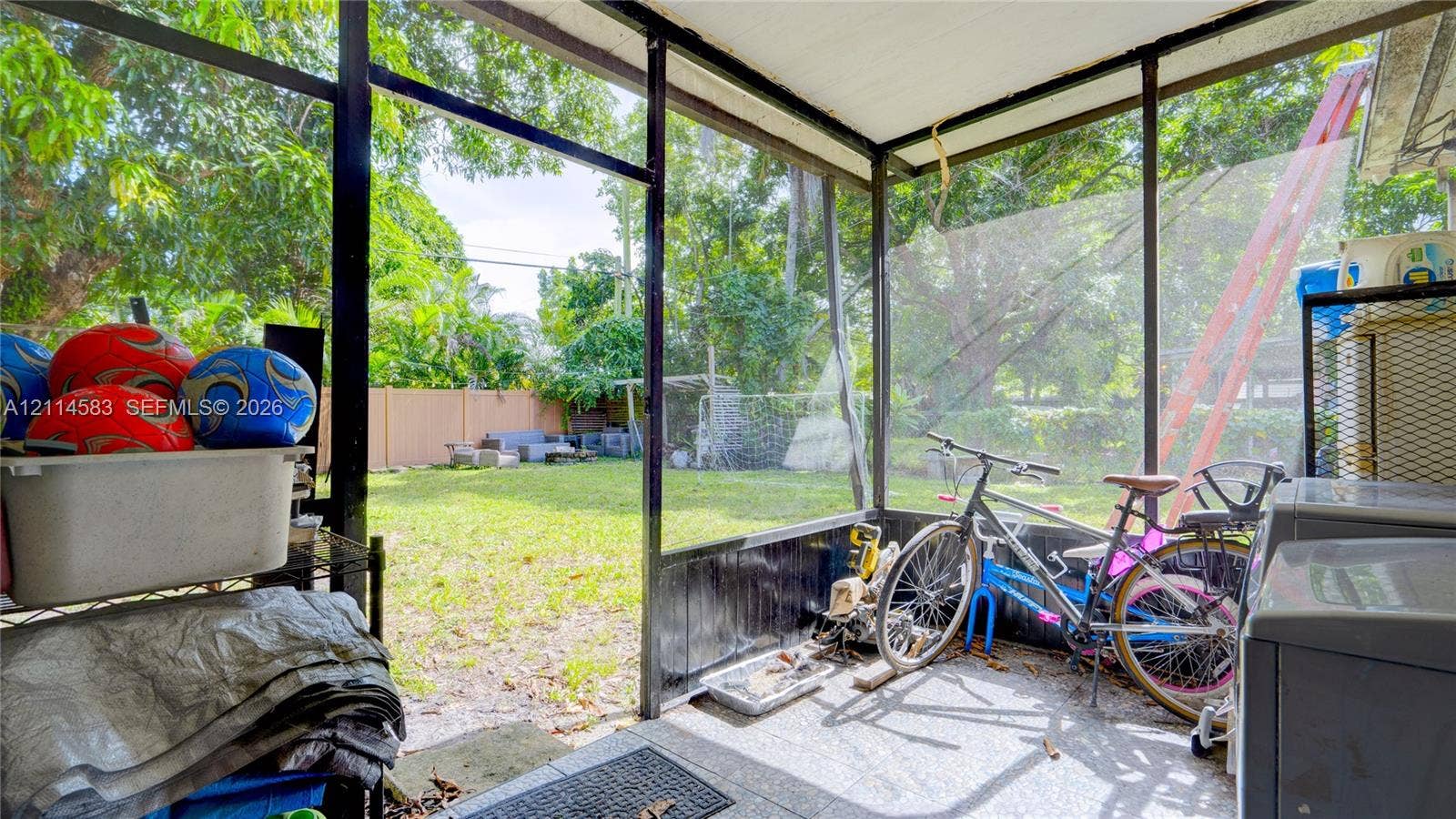 13301 NW Miami Court, Miami, FL 33168 Screened-in porch featuring concrete flooring and a fenced backyard