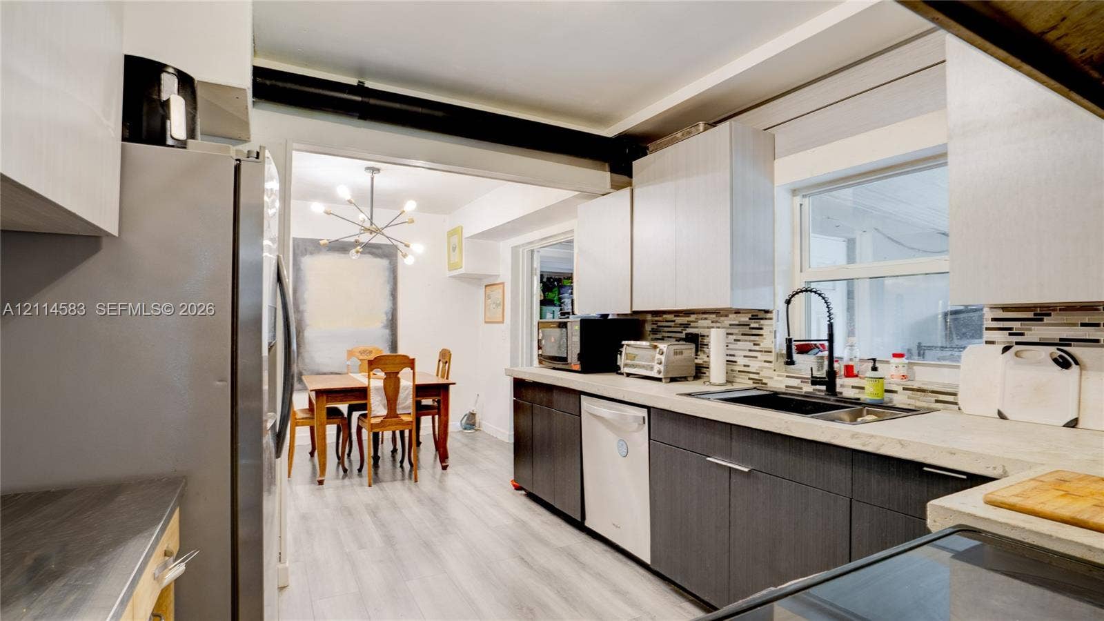 13301 NW Miami Court, Miami, FL 33168 Kitchen featuring dual-tone cabinetry, stone-finish countertops, linear tile backsplash, stainless steel appliances, and a gooseneck faucet