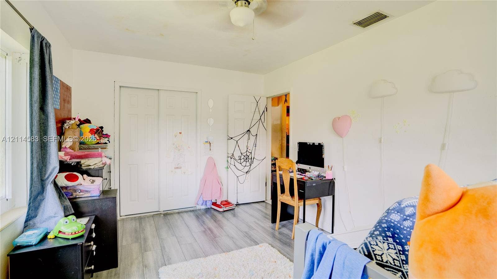 13301 NW Miami Court, Miami, FL 33168 Room featuring wood-finish flooring, a ceiling fan with integrated lighting, and a dual-panel closet