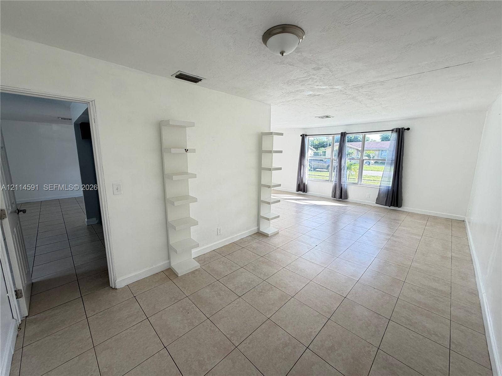 Open floor plan featuring tile flooring, built-in wall shelving, and large windows providing natural light