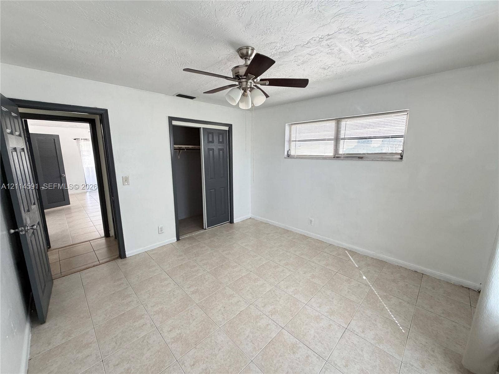 Neutral interior featuring tile flooring, a multi-light ceiling fan, sliding closet doors, and dark-toned door frames