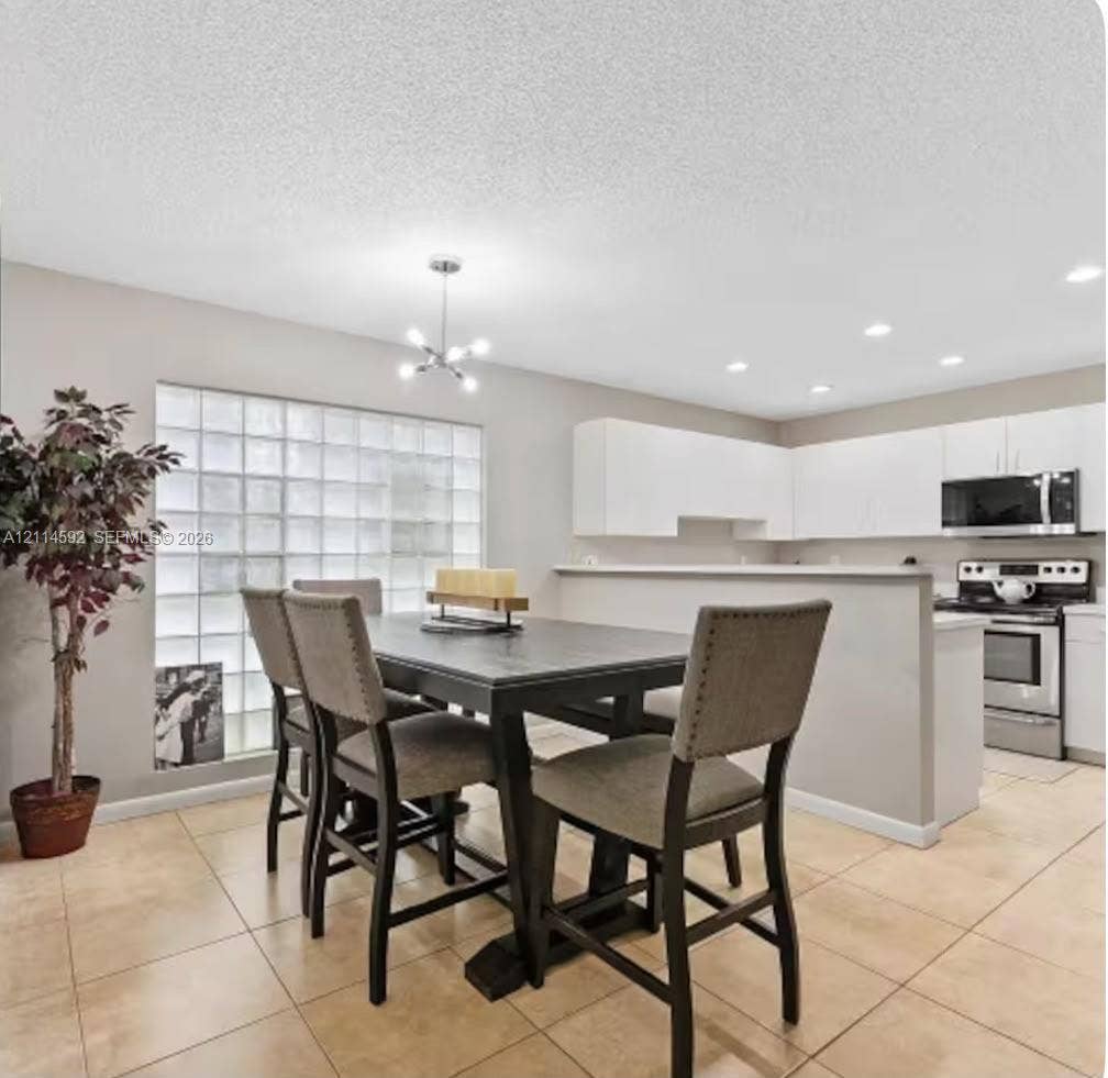 12230 Dartmoor Drive, Wellington, FL 33414 Kitchen featuring white cabinetry, stainless steel appliances, tile flooring, glass block window detailing, and recessed lighting