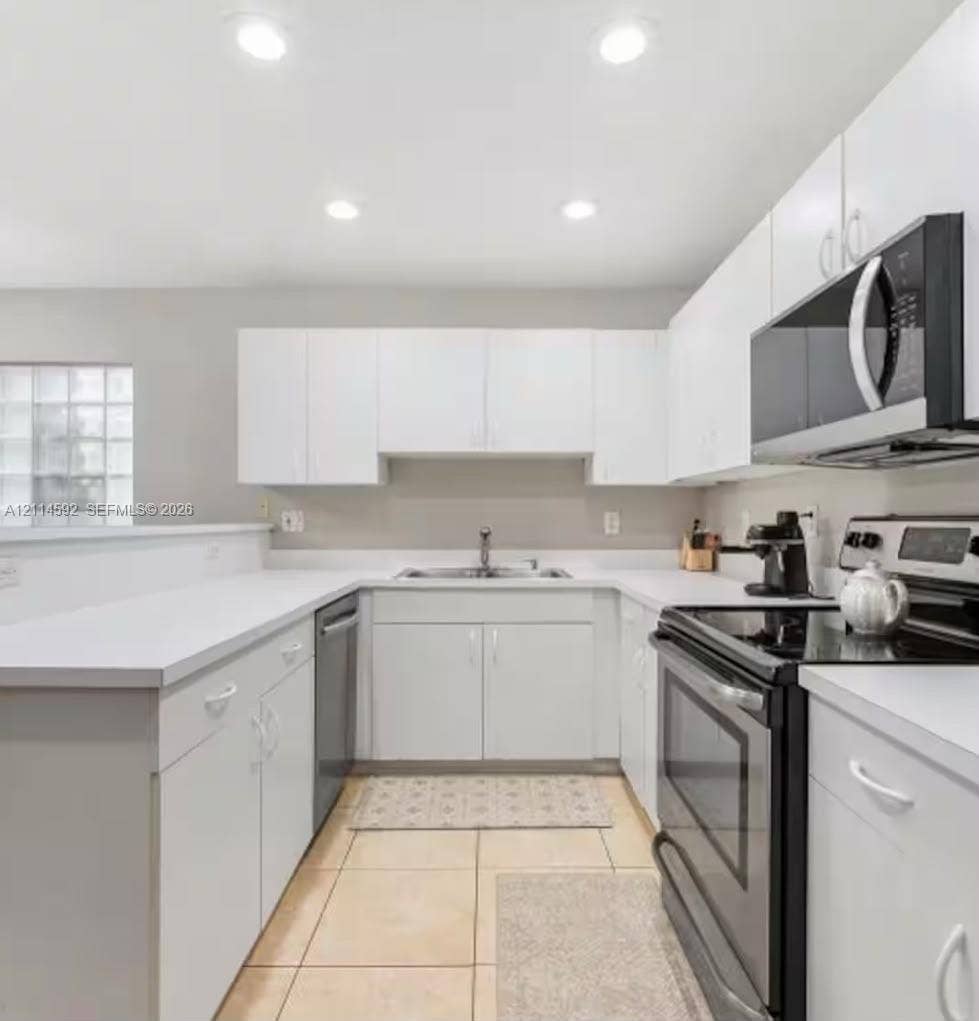 12230 Dartmoor Drive, Wellington, FL 33414 Kitchen featuring white cabinetry, solid-surface countertops, recessed ceiling lighting, a stainless steel over-the-range microwave, and ceramic tile flooring