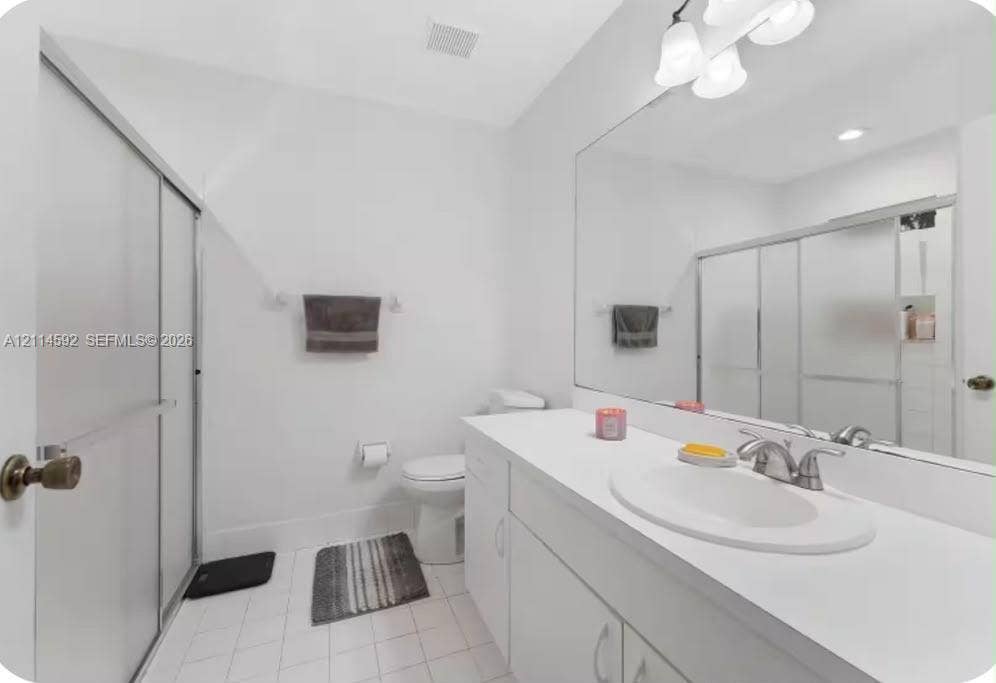 12230 Dartmoor Drive, Wellington, FL 33414 Full-width mirror, white cabinetry with solid-surface countertop, integrated vanity sink, brushed-metal faucet, and walk-in shower enclosure